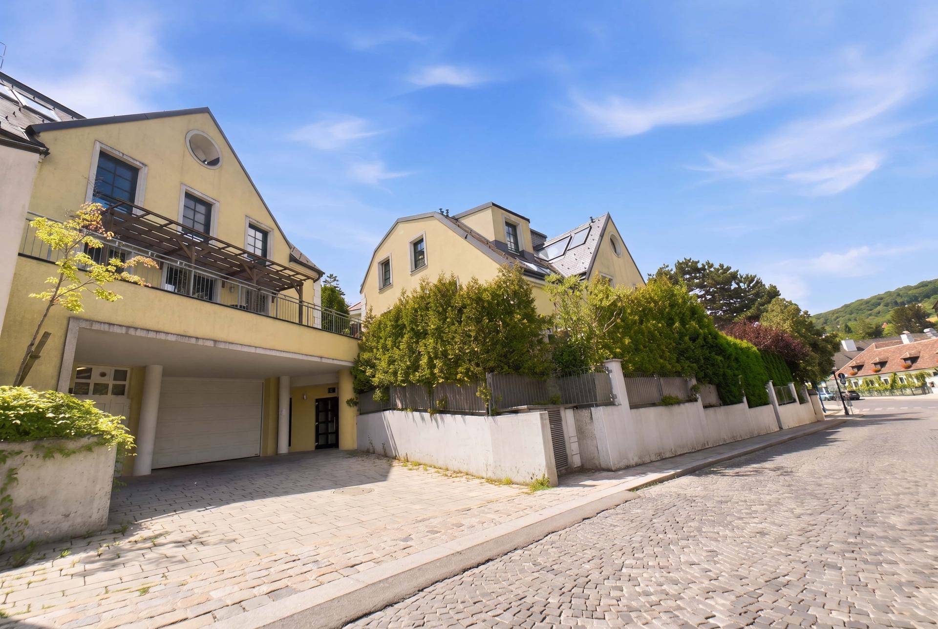 Mehrere Gebäude mit gelber Fassade und gepflasterter Straße unter blauem Himmel.