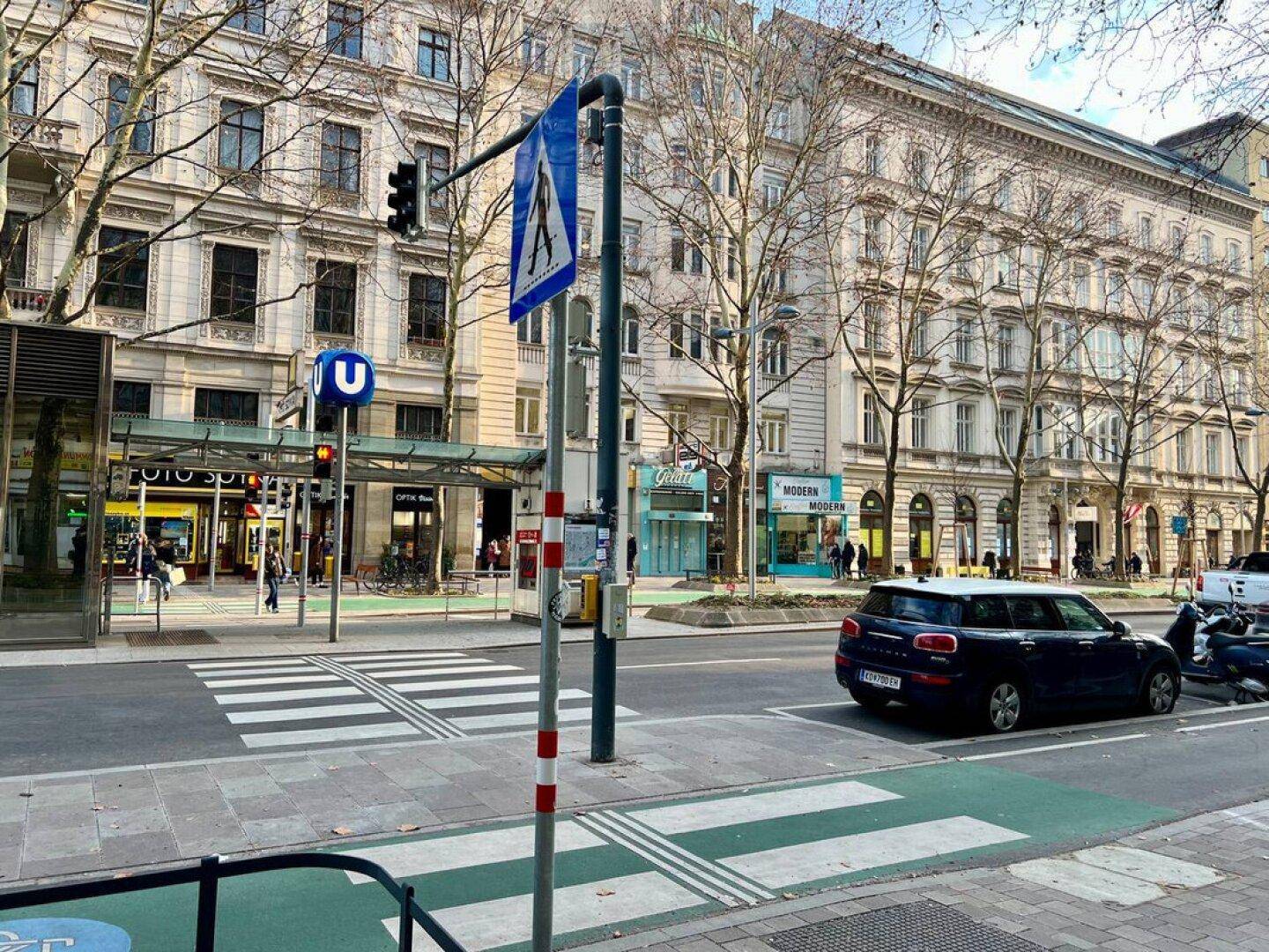 Belebtes Stadtbild mit U-Bahn-Station, Geschäften und historischen Gebäuden.