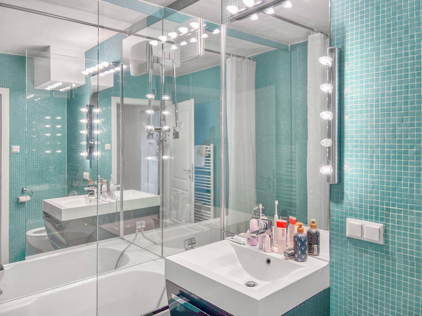 Modernes Badezimmer mit türkisfarbenen Mosaikfliesen, Waschbecken und großem Spiegelschrank.