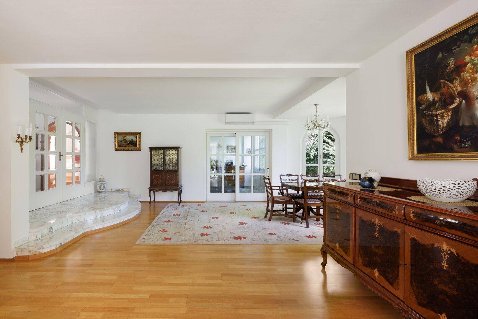 Geräumiger Flur mit Holzfußboden, eleganten Möbeln und Übergang zum Essbereich.