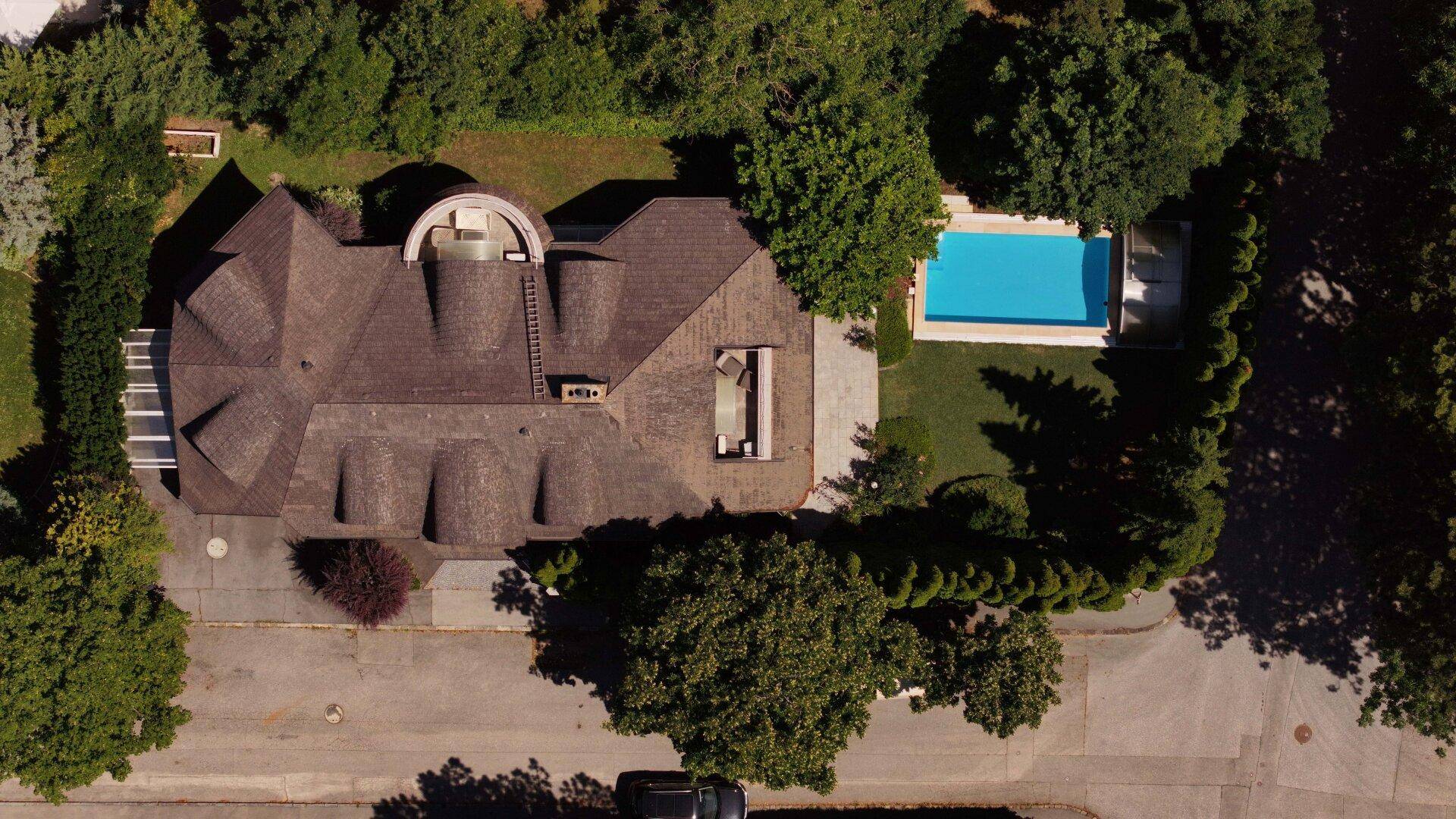Luftaufnahme eines Anwesens mit großem Haus, Swimmingpool und gepflegtem Gartenbereich.