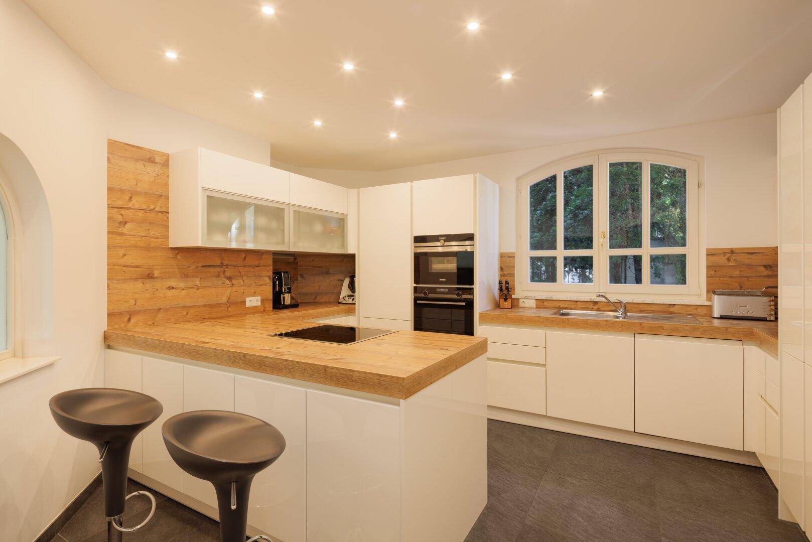 Moderne Küche mit weißen Schränken, Holz-Arbeitsplatten und integrierten Geräten.