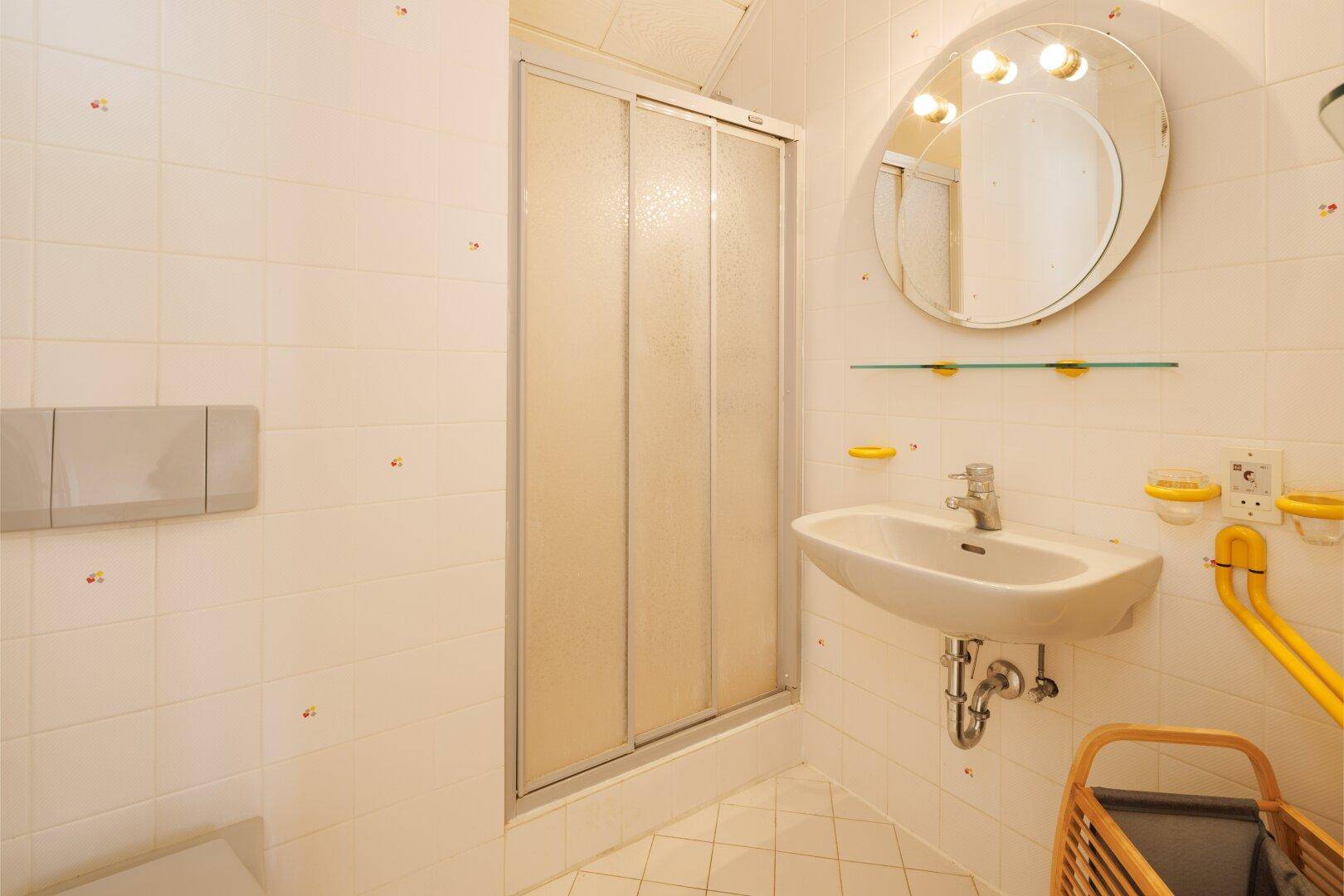 Funktionales Badezimmer mit Duschkabine, Waschbecken und hellen Fliesen.