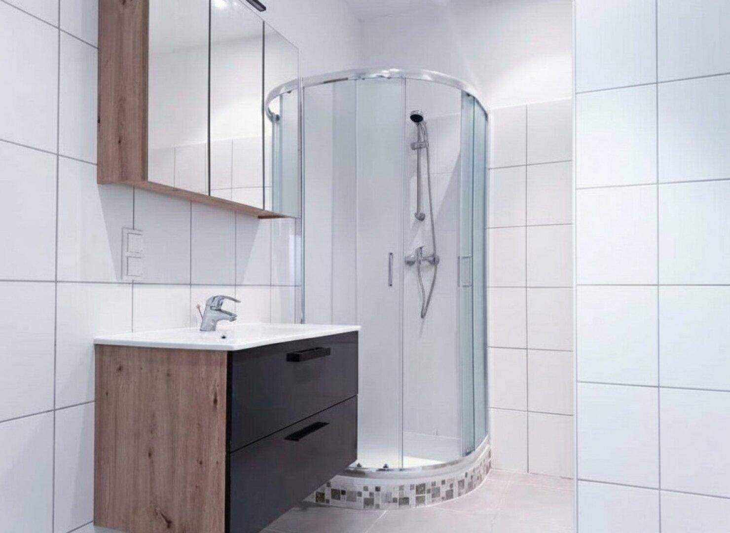 Modernes Badezimmer mit weiß gefliesten Wänden, Duschkabine und Holzwaschtisch mit Spiegelschrank.