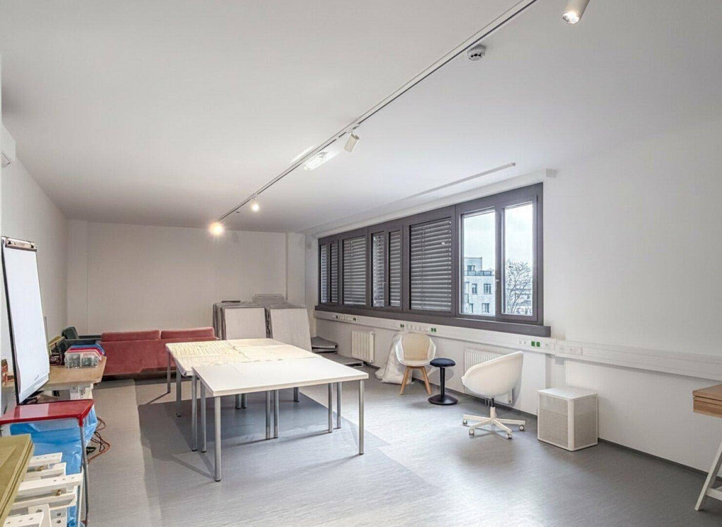 Vielseitiger Raum mit Tischen, Stühlen und Lagerflächen, ideal für kreative Projekte oder Büronutzung.