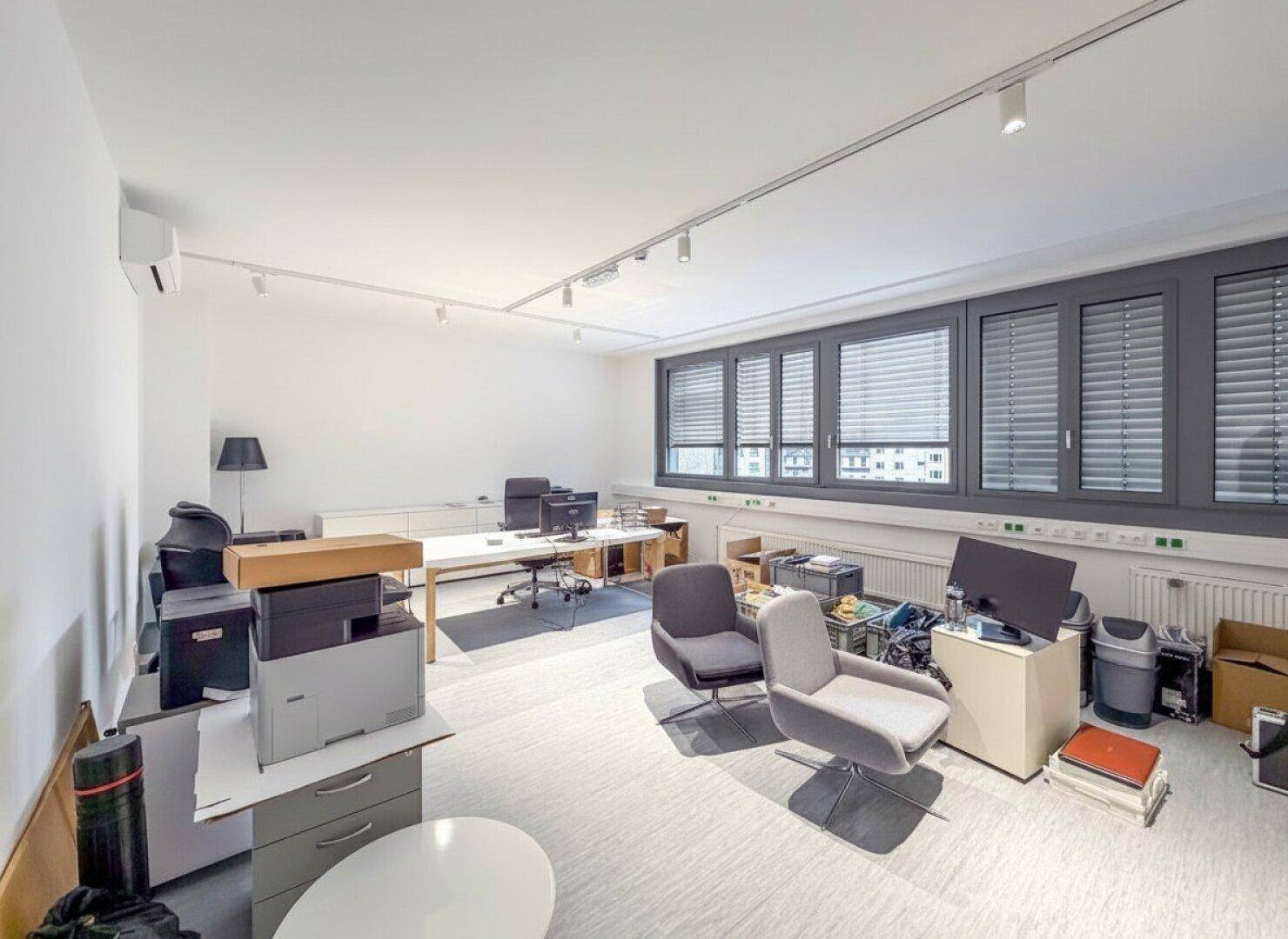 Modernes Büro mit mehreren Arbeitsplätzen, bequemen Stühlen und Klimaanlage, bereit zur Nutzung.