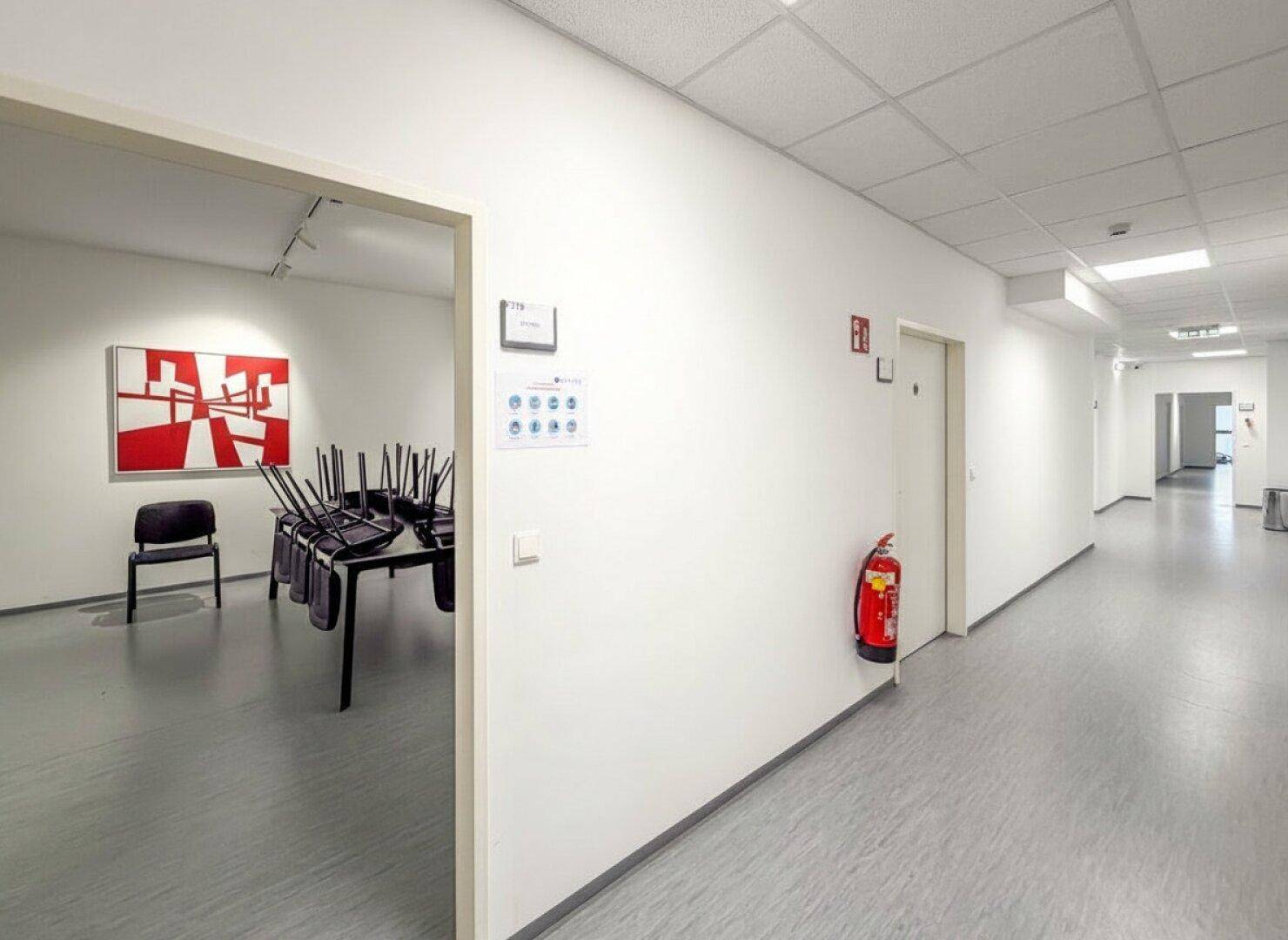 Heller Flur mit Zugang zu einem Raum, der für Besprechungen oder Schulungen genutzt werden kann.