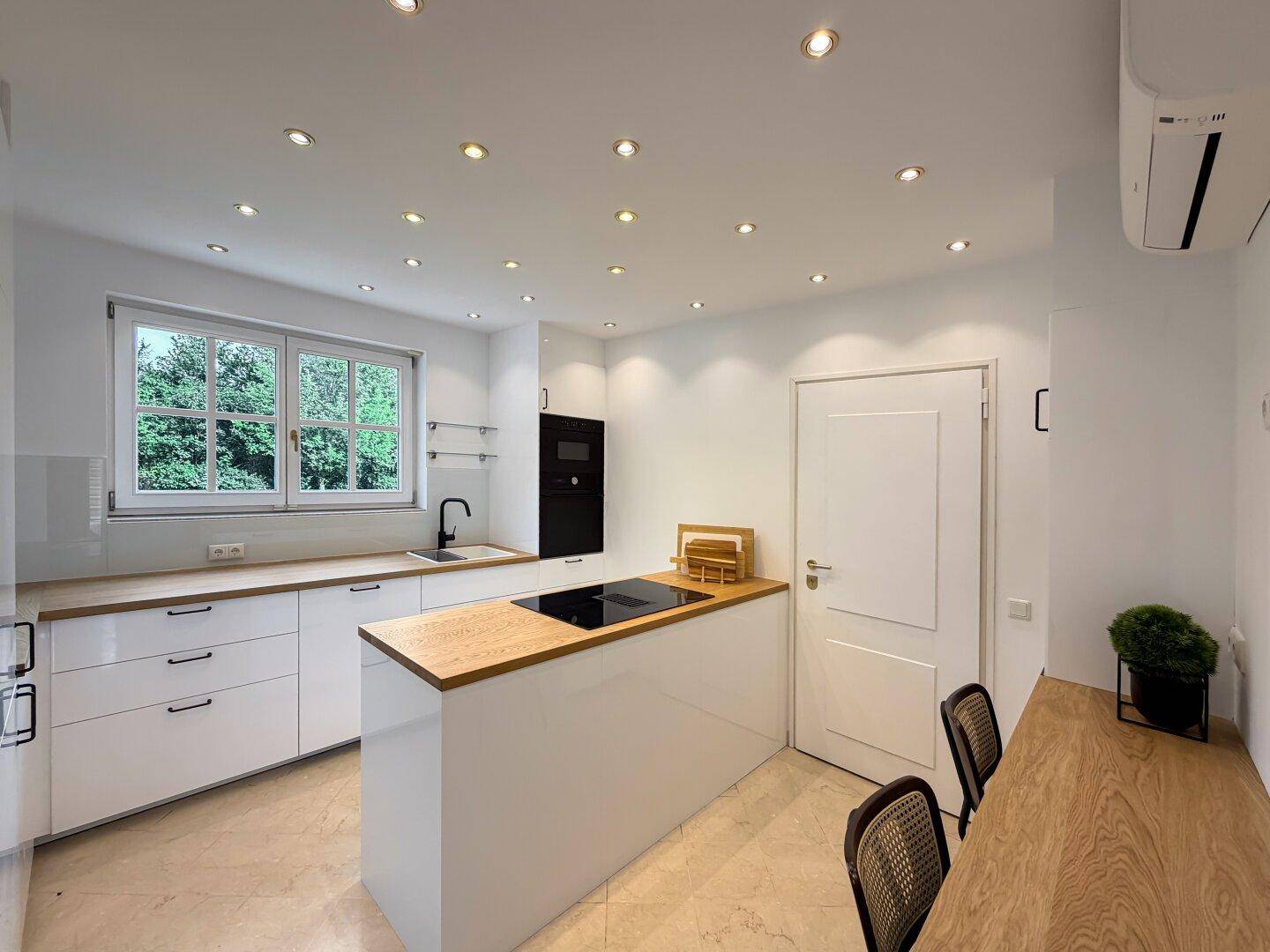 Moderne Küche mit weißen Schränken, Holz-Arbeitsplatten und Induktionskochfeld.