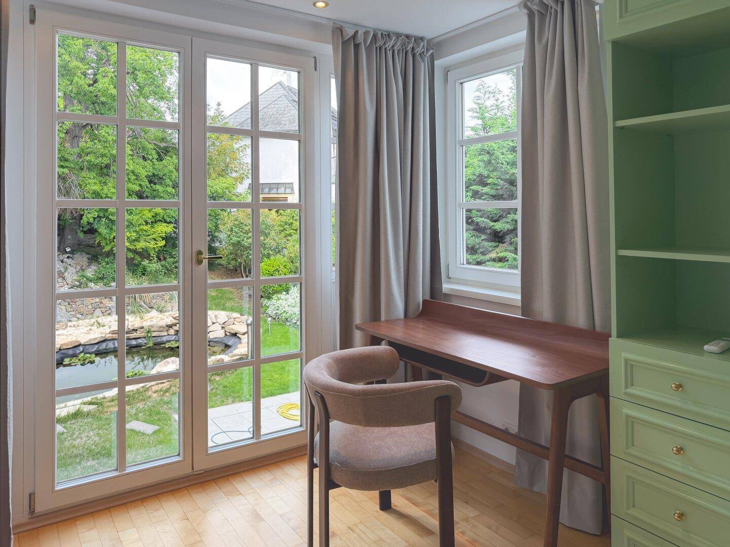Heller Arbeitsplatz mit Schreibtisch, Gartenblick und Zugang zu einem Außenbereich.