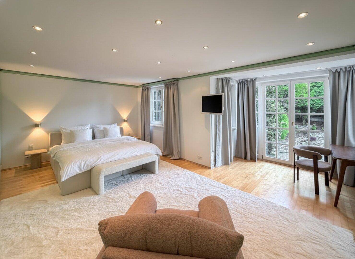 Helles Schlafzimmer mit Holzboden, großem Bett und Zugang zum Garten.