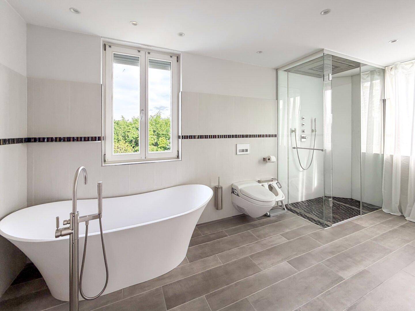 Modernes Badezimmer mit freistehender Badewanne, großer Dusche und Fenster.