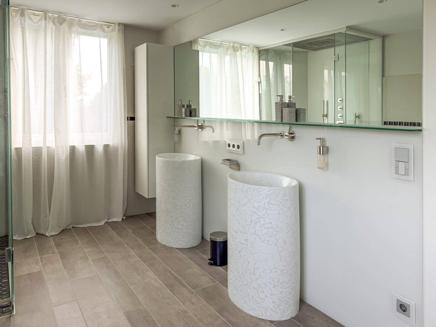 Elegantes Badezimmer mit zwei modernen Säulenwaschbecken und großem Spiegel.