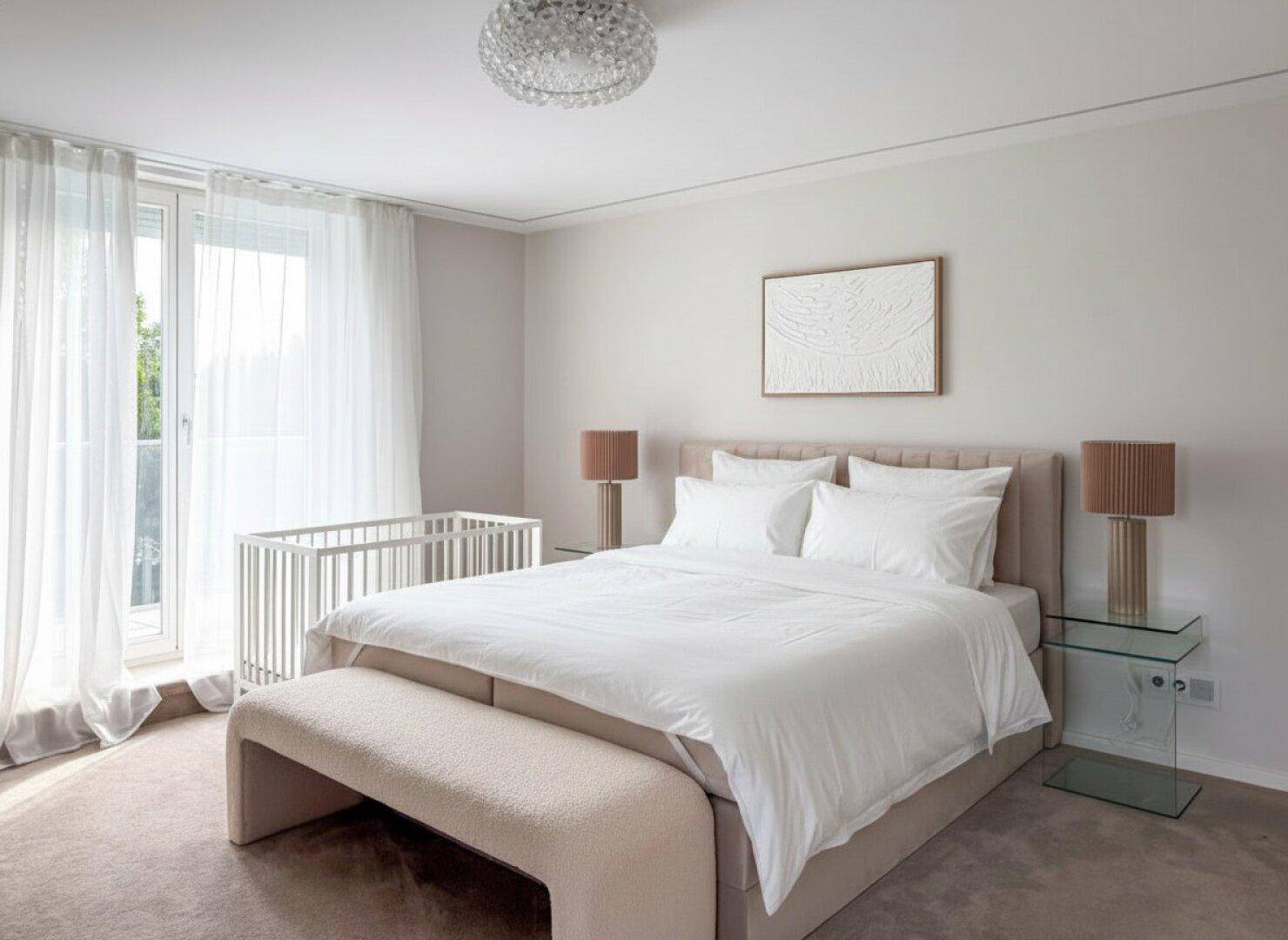 Ruhiges Schlafzimmer mit Doppelbett, beigem Teppichboden und Zugang zum Balkon.