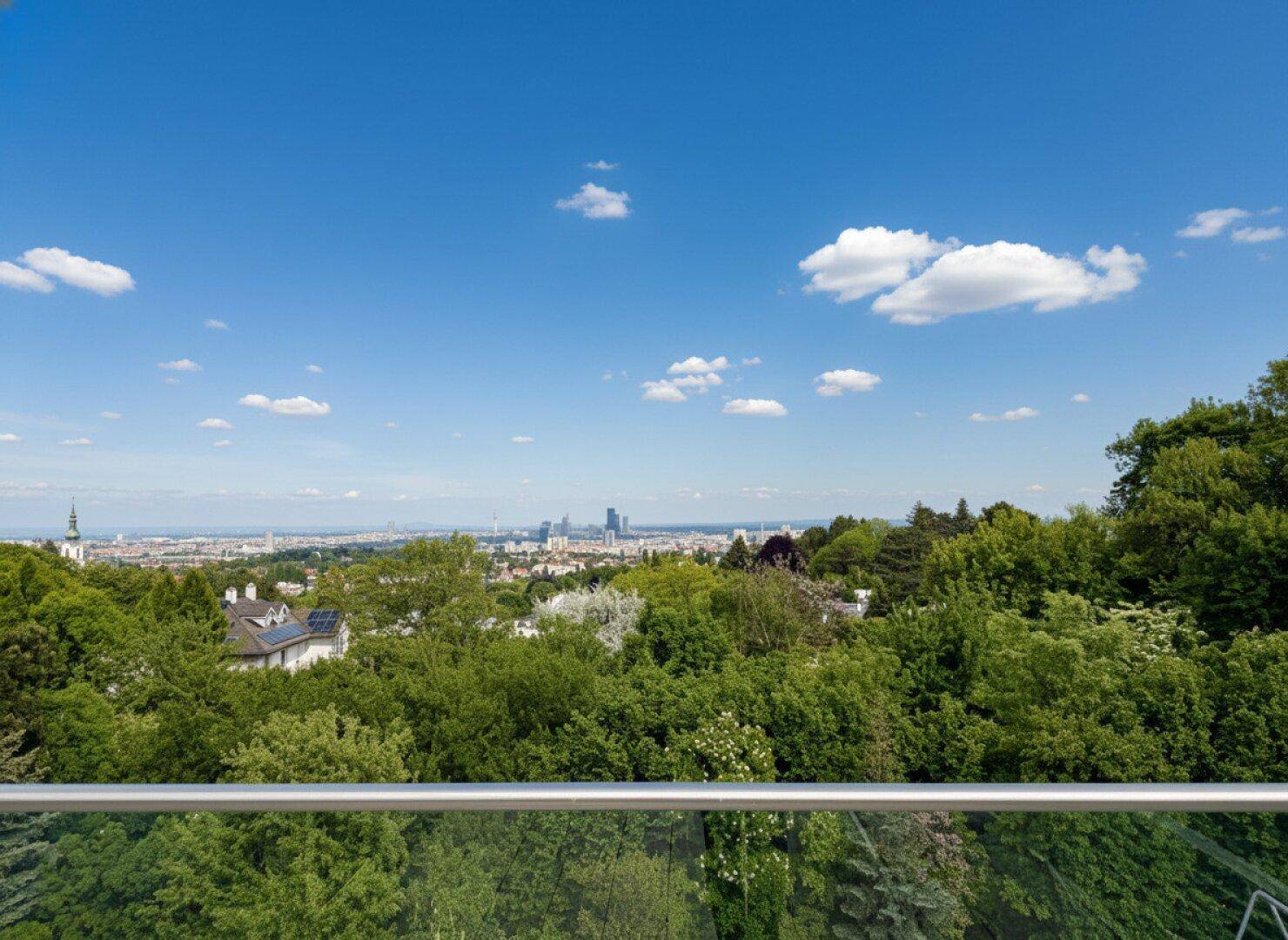 Panoramablick über die grüne Landschaft und die Stadt am Horizont unter blauem Himmel.