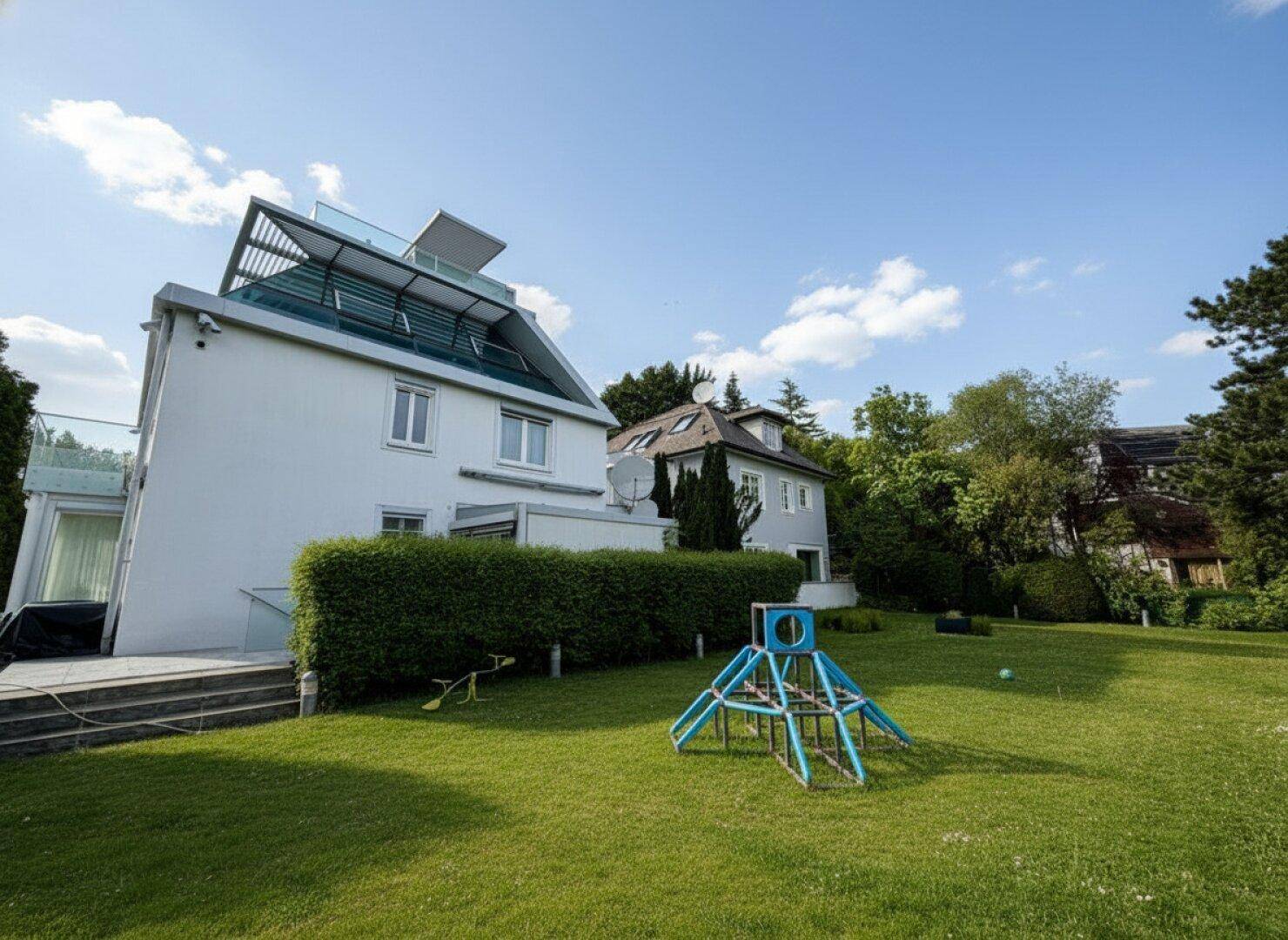 Großer Garten mit Rasenfläche, Kinderspielgerät und Blick auf das moderne Haus.