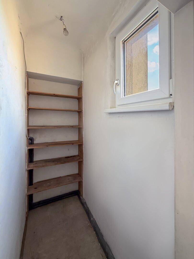 Kleiner Abstellraum mit Holzregalen und einem Fenster, das für natürliche Belüftung sorgt.