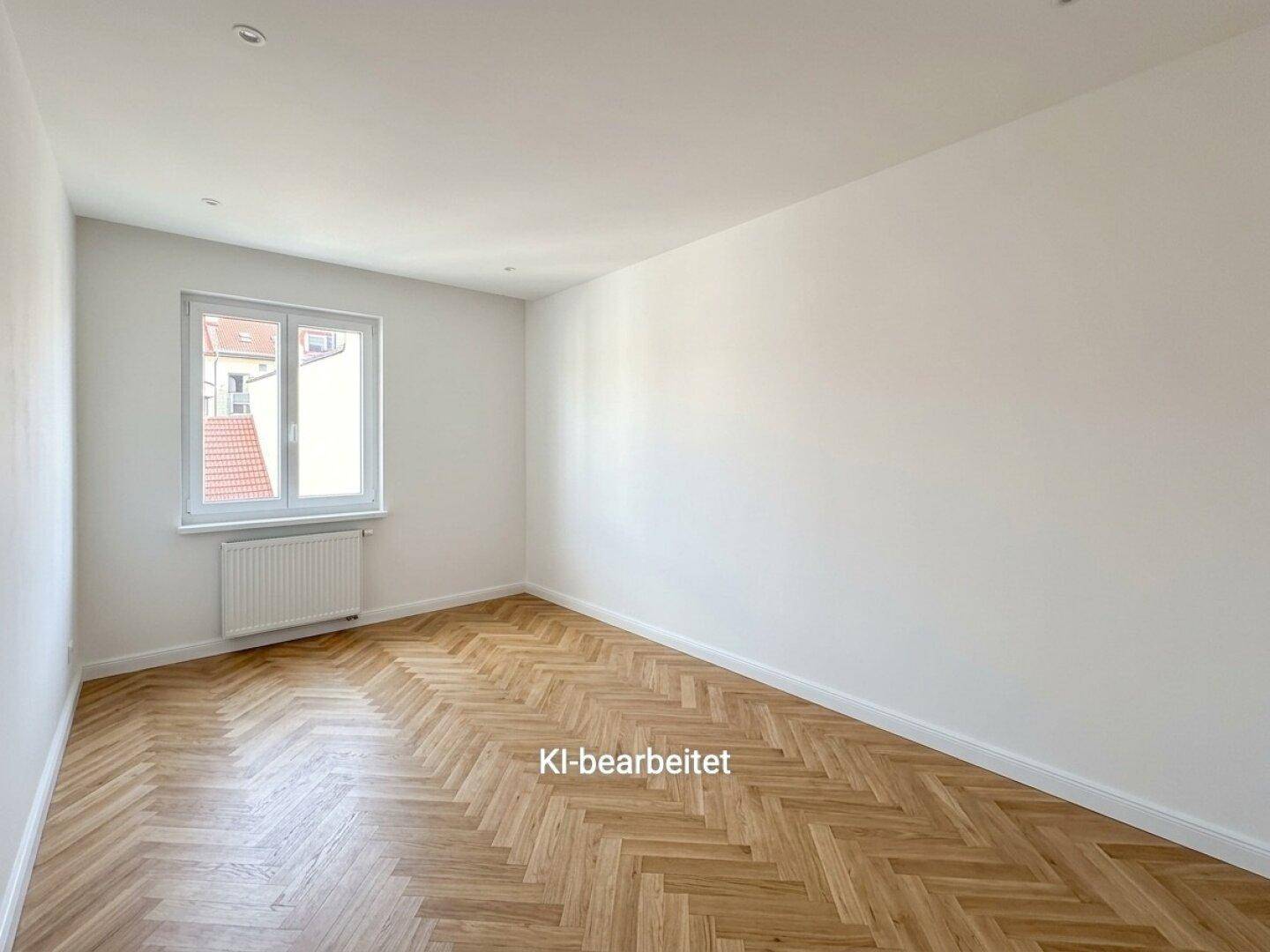 Geräumiges Zimmer mit hellem Fischgrätparkett und einem Fenster, das viel Tageslicht hereinlässt.