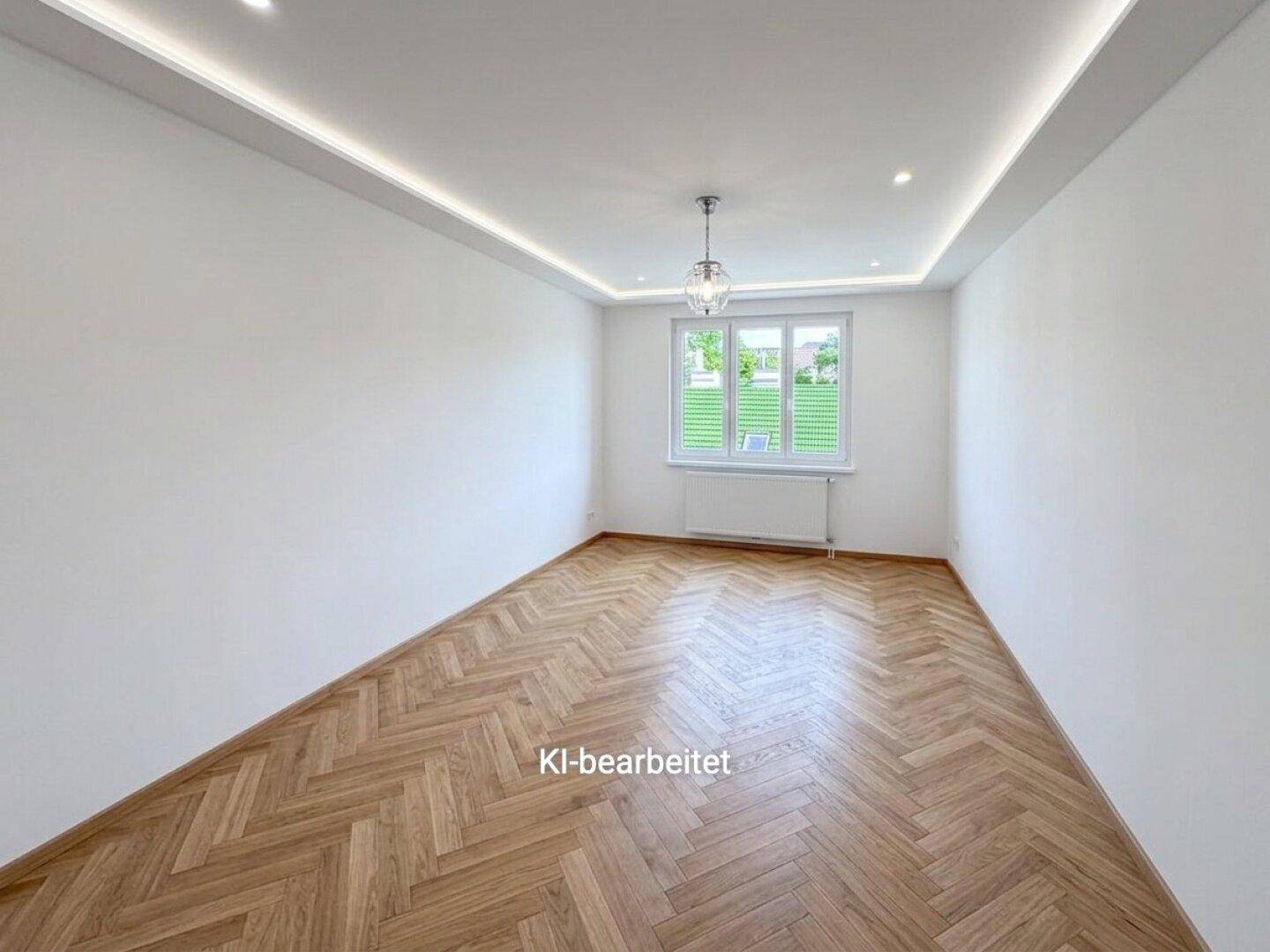 Helles Zimmer mit Fischgrätparkett, modernen Deckenleuchten und einem Fenster mit Jalousien.