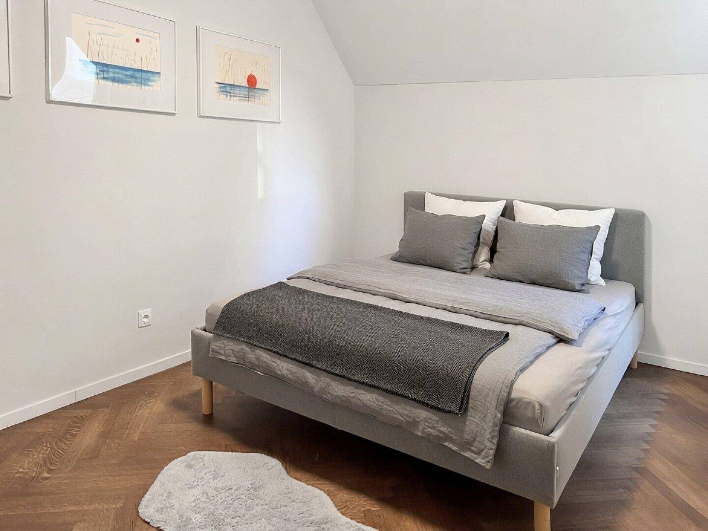 Gemütliches Schlafzimmer mit modernem Bett, Parkettboden und minimalistischer Dekoration.