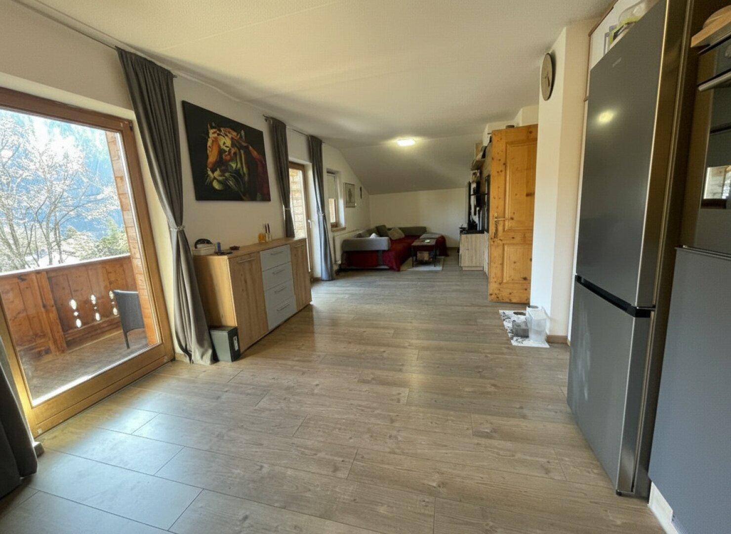 Heller Wohnbereich mit Laminatboden und Zugang zu einem Balkon, ideal für entspannte Stunden.