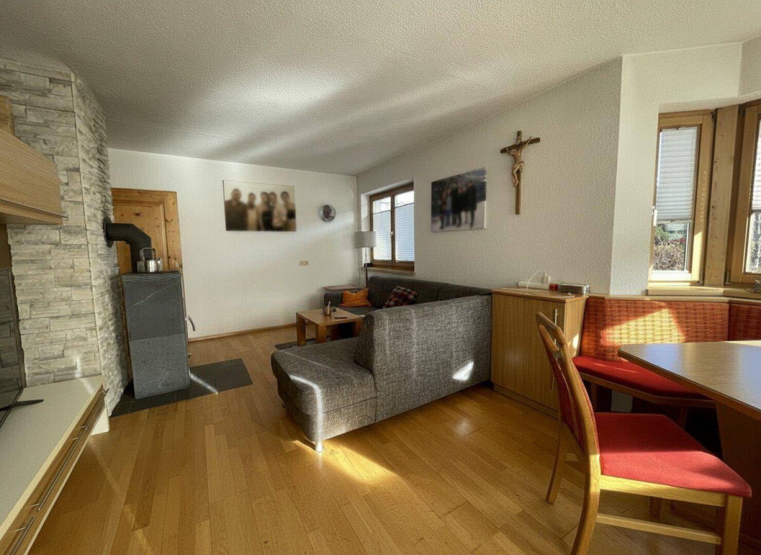 Wohnzimmer mit modernem Holzofen, Holzboden und großen Fenstern für viel Tageslicht.