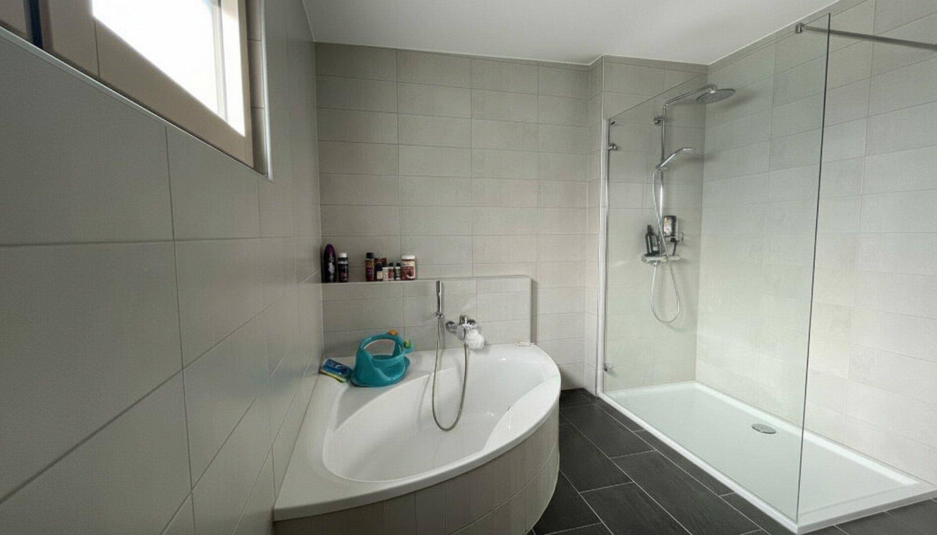 Modernes Badezimmer mit Eckbadewanne, ebenerdiger Dusche und Fenster.