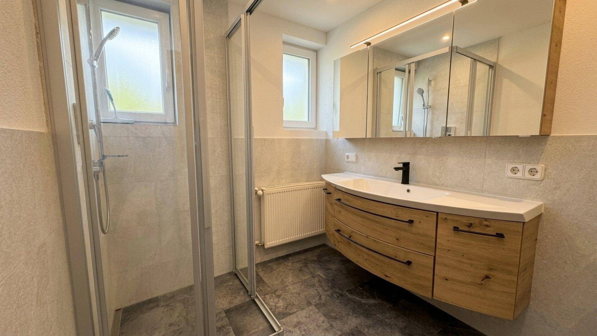 Modernes Badezimmer mit Duschkabine, Holzwaschtisch und Spiegelschrank.