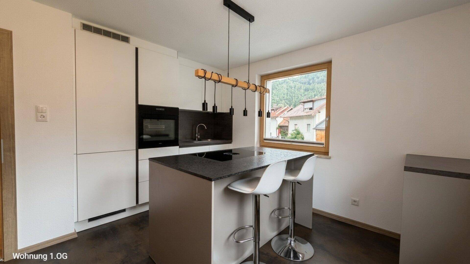 Moderne Küche mit Kücheninsel, integrierten Geräten und Fensterblick.