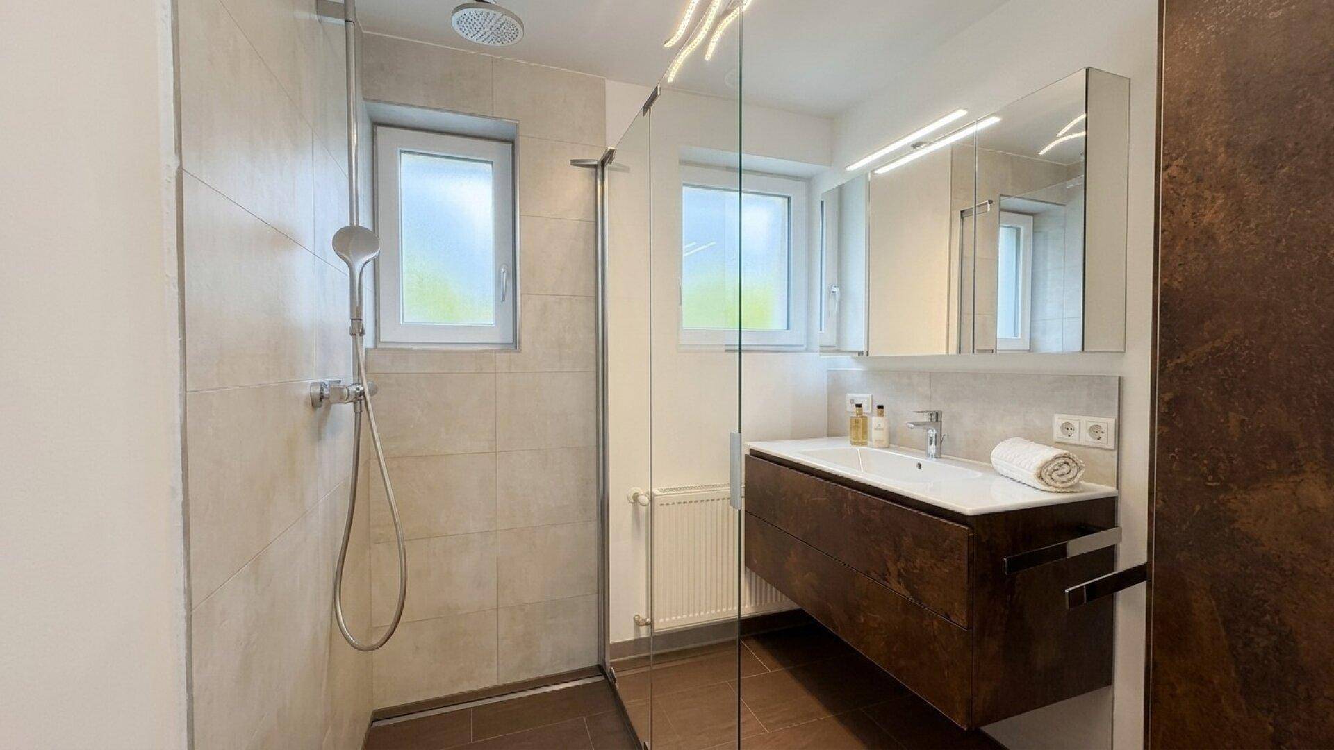Modernes Badezimmer mit ebenerdiger Dusche, Waschtisch und Spiegelschrank.