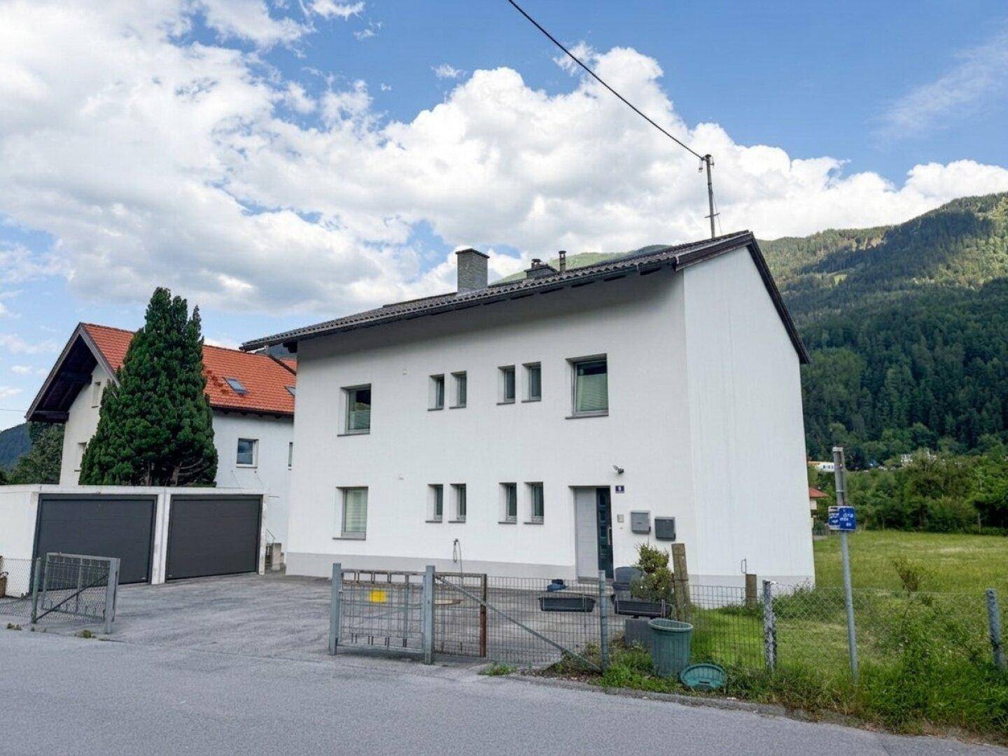 Wohnhausfassade mit Eingangsbereich und Blick auf die umliegende Berglandschaft.