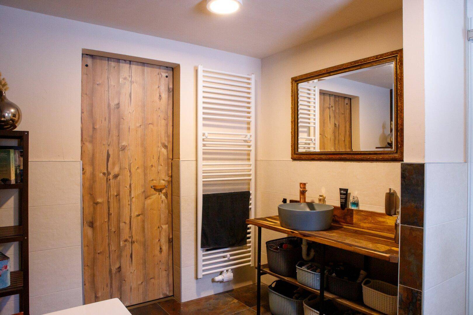 Modernes Badezimmer mit Holzwaschtisch, Aufsatzwaschbecken und beheiztem Handtuchhalter.