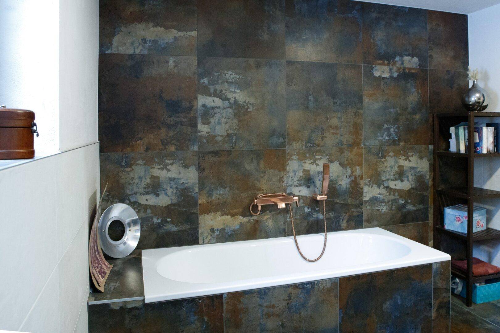 Badezimmer mit Badewanne und auffälligen, großformatigen Fliesen in Rostoptik.