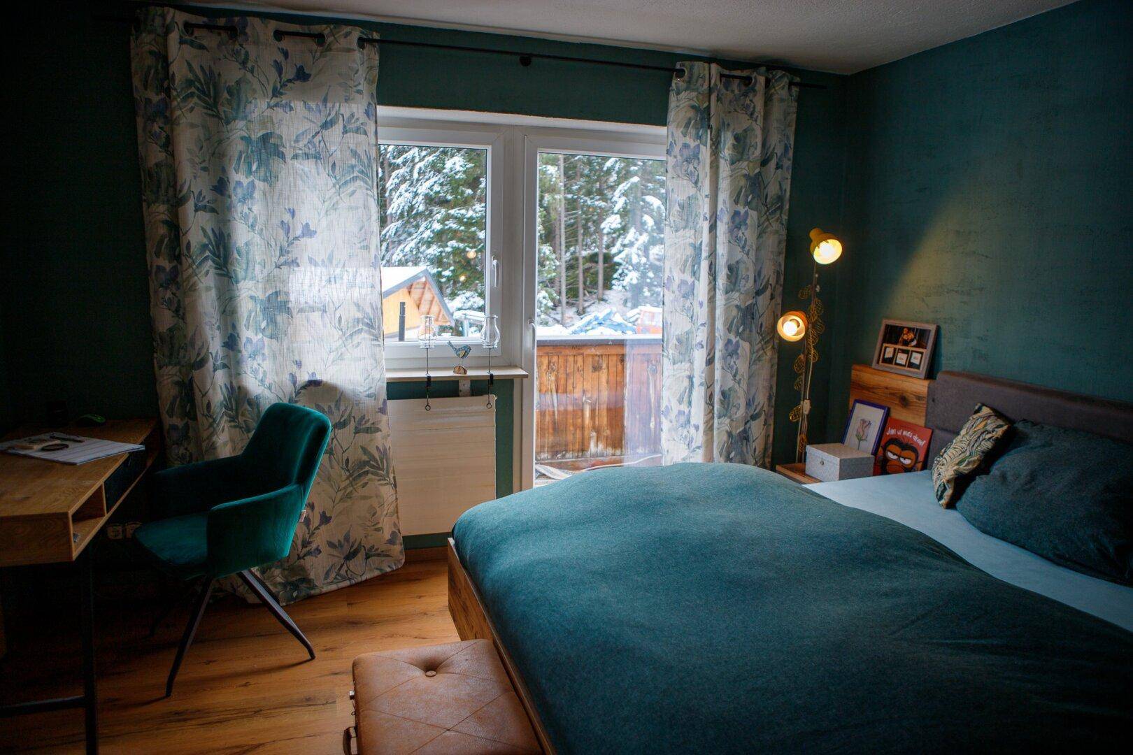 Schlafzimmer mit Doppelbett, Schreibtisch und Zugang zu einem Balkon.