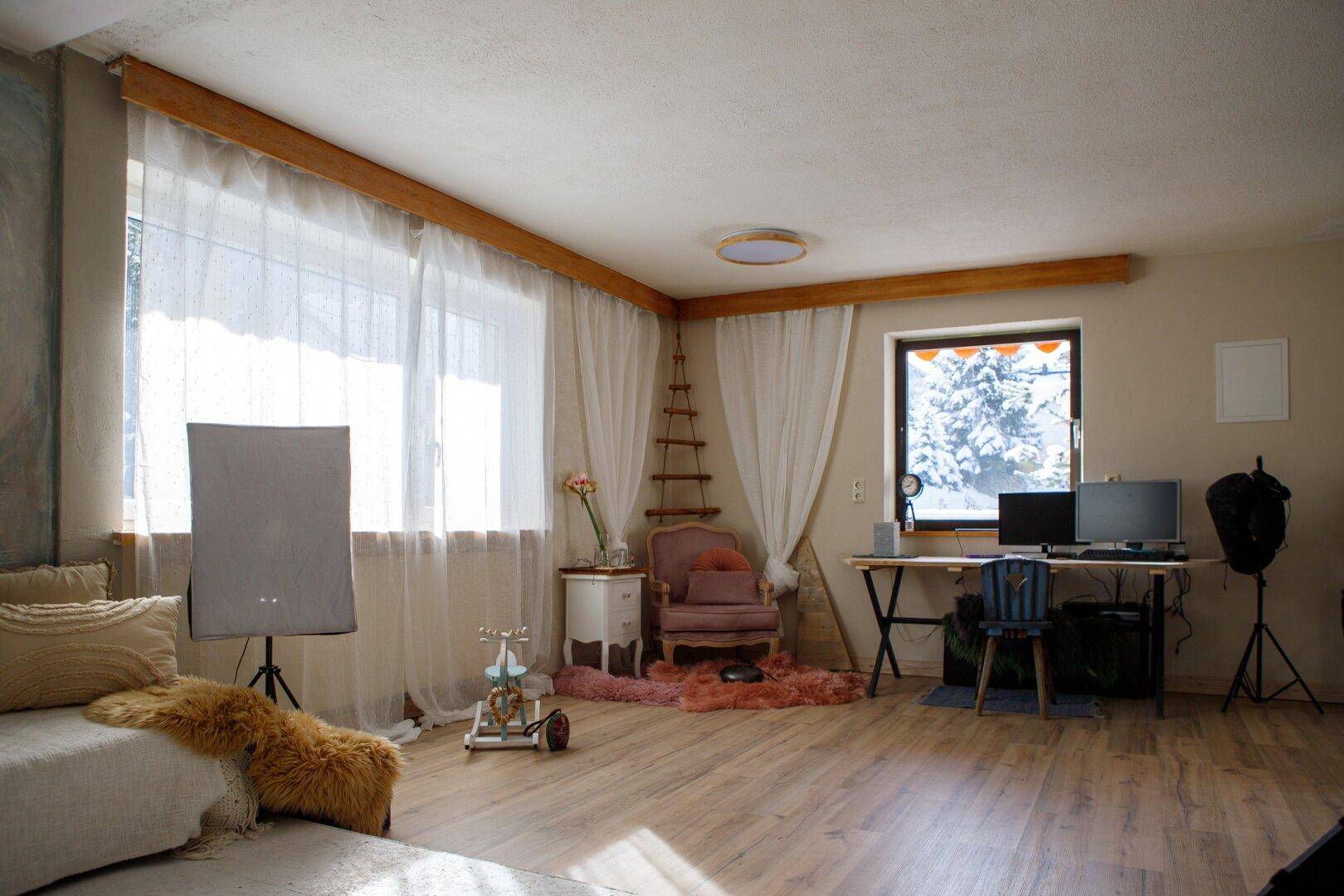 Heller Raum mit großen Fenstern, Holzboden und vielseitiger Nutzungsmöglichkeit.