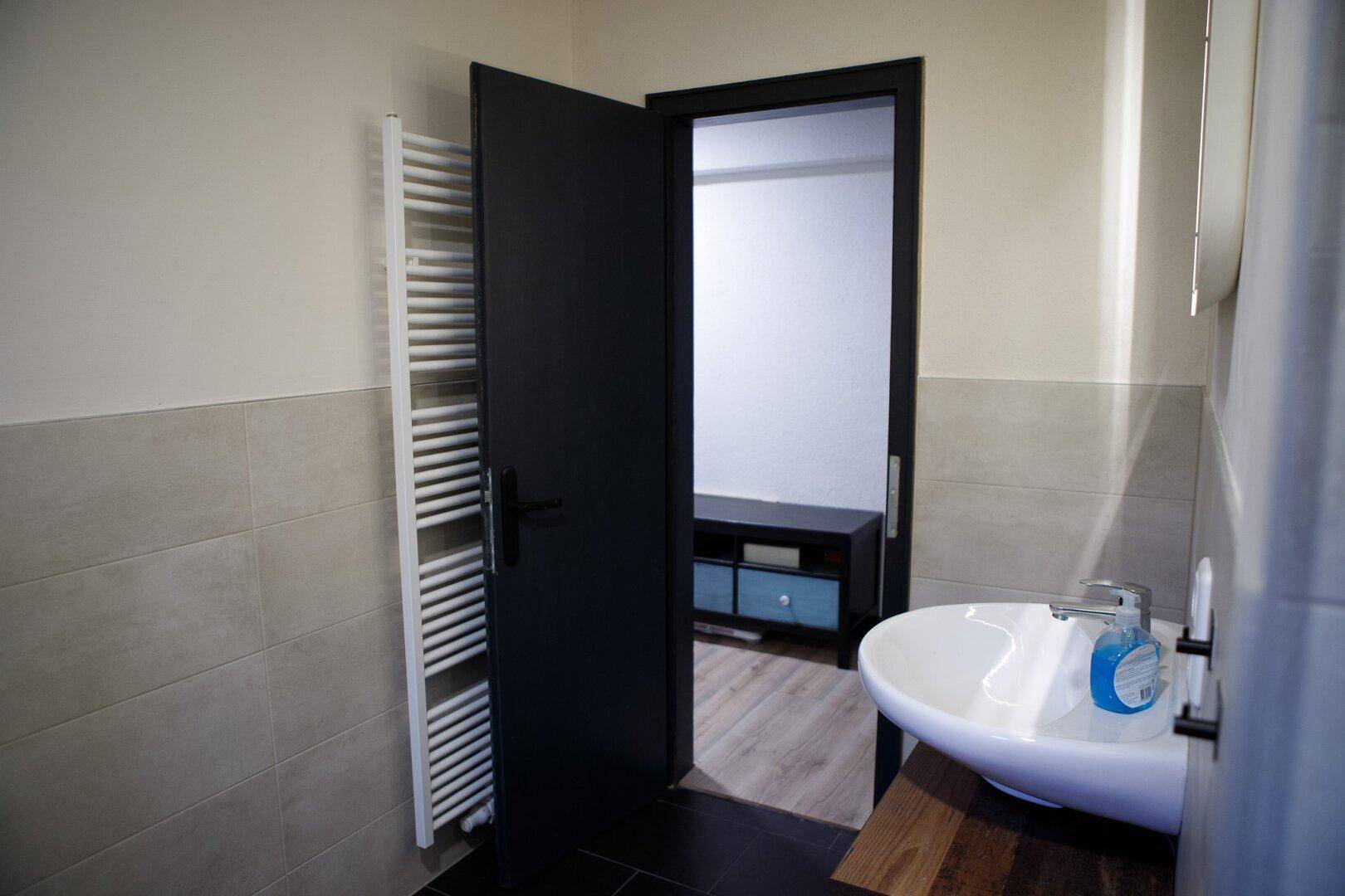 Badezimmer mit Waschbecken, Spiegel und beheiztem Handtuchhalter.