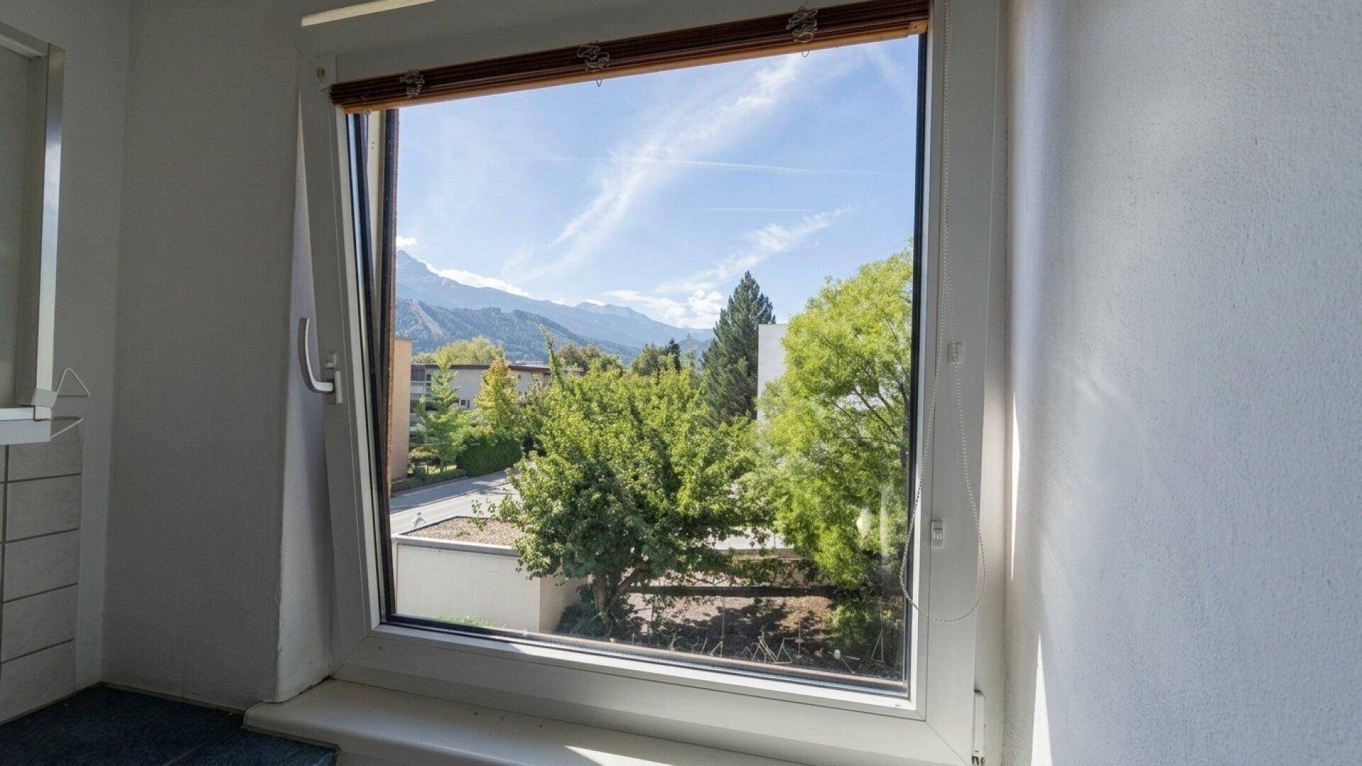 Großes Fenster mit weitem Blick auf die Berge und grüne Landschaft.