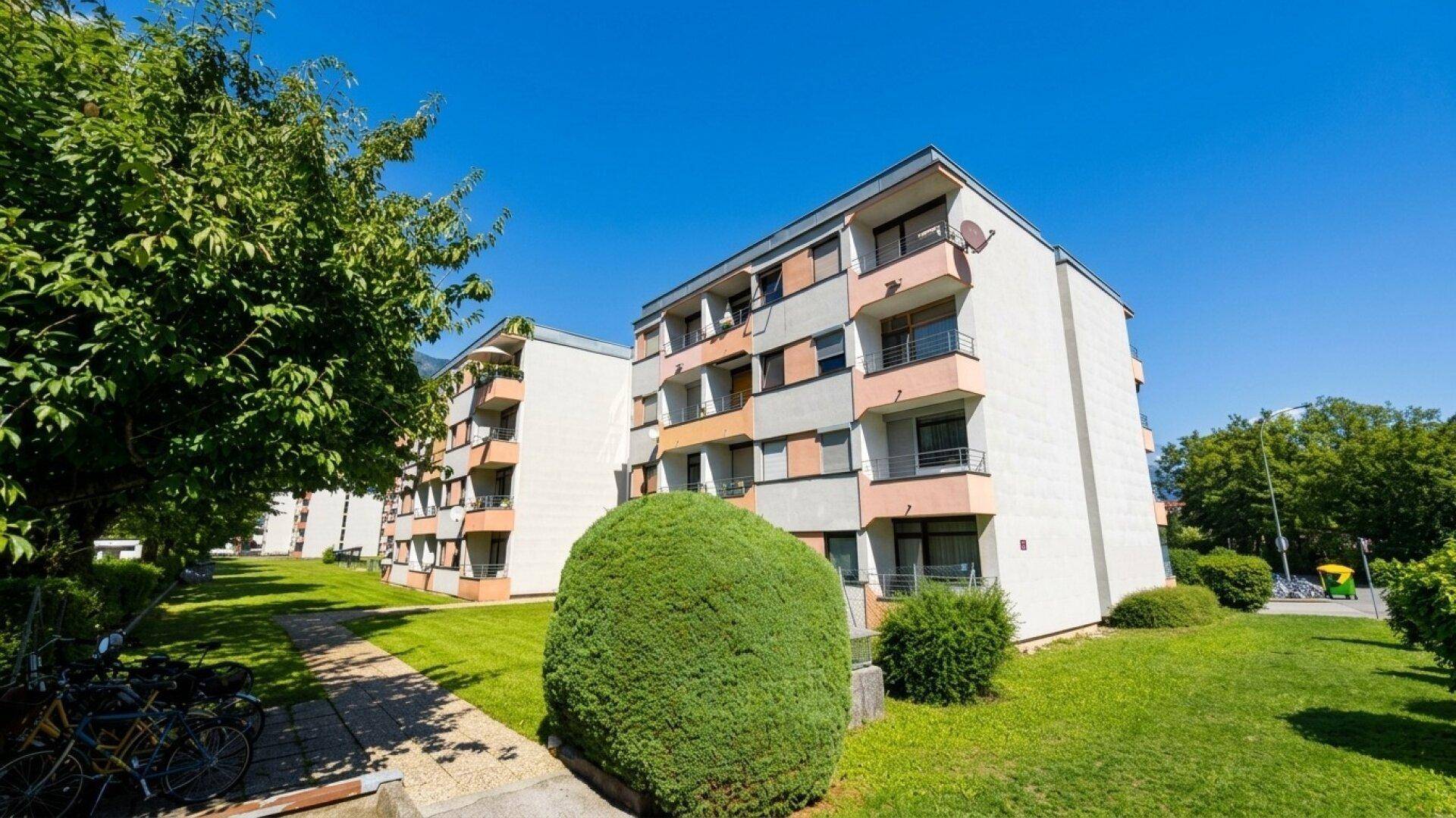 Außenansicht eines Mehrfamilienhauses mit Balkonen und gepflegter Grünanlage.