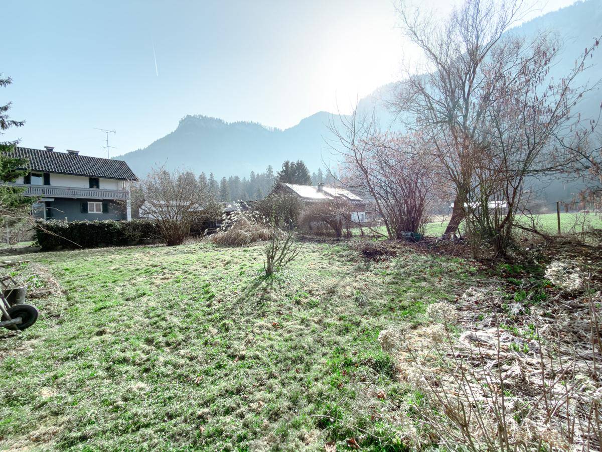 Großer Gartenbereich mit Bergblick und einem Wohnhaus in der Ferne.