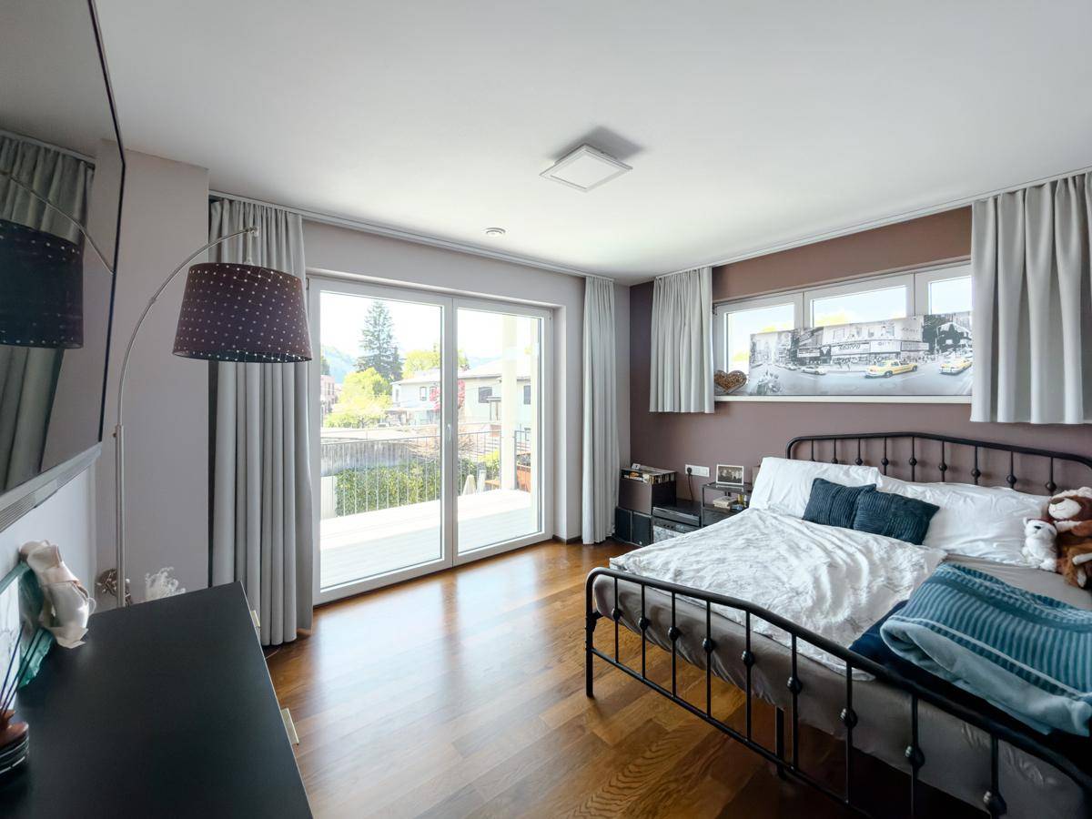 Gemütliches Schlafzimmer mit Doppelbett, Holzboden und Zugang zu einem Balkon.