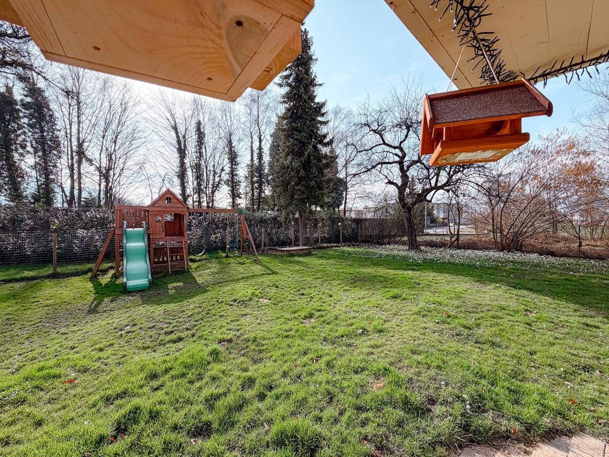 Großer, sonniger Garten mit Spielplatz und Rasenfläche, ideal für Kinder und Entspannung.