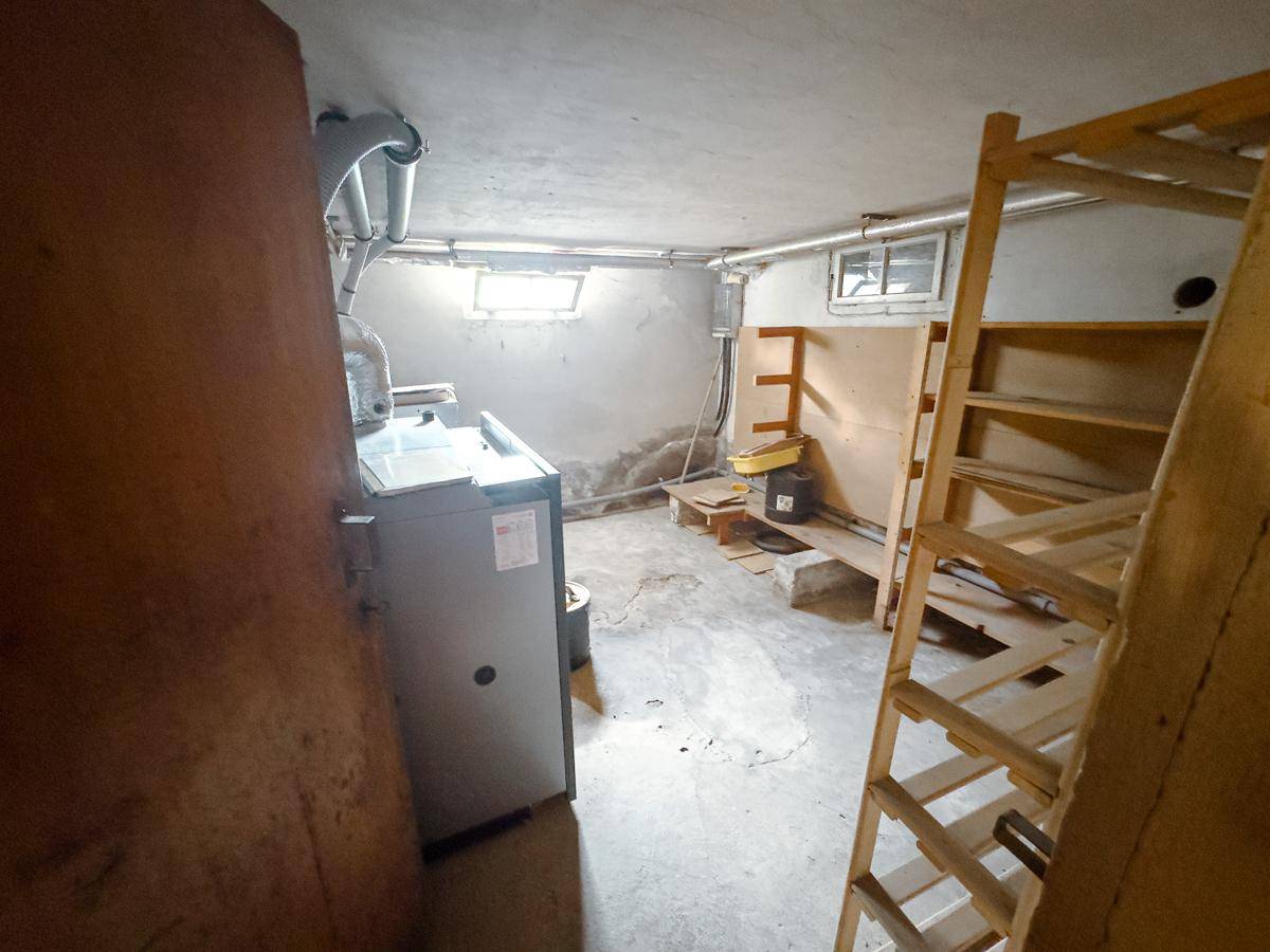 Technikraum im Keller mit Heizungsanlage, Betonboden und kleinen Fenstern.