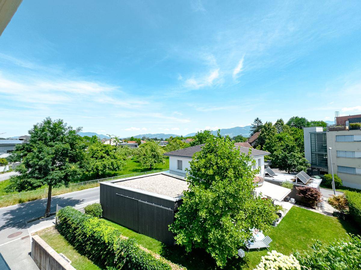 Ausblick auf die umliegende Wohnbebauung mit Gärten, Bäumen und einem modernen Gebäude.