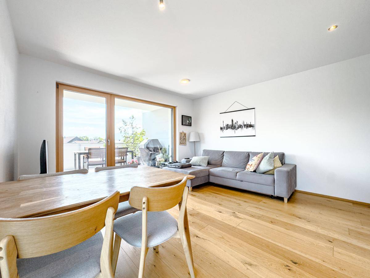 Offener Wohn-Essbereich mit Holzboden, Sofa und Zugang zur Terrasse.