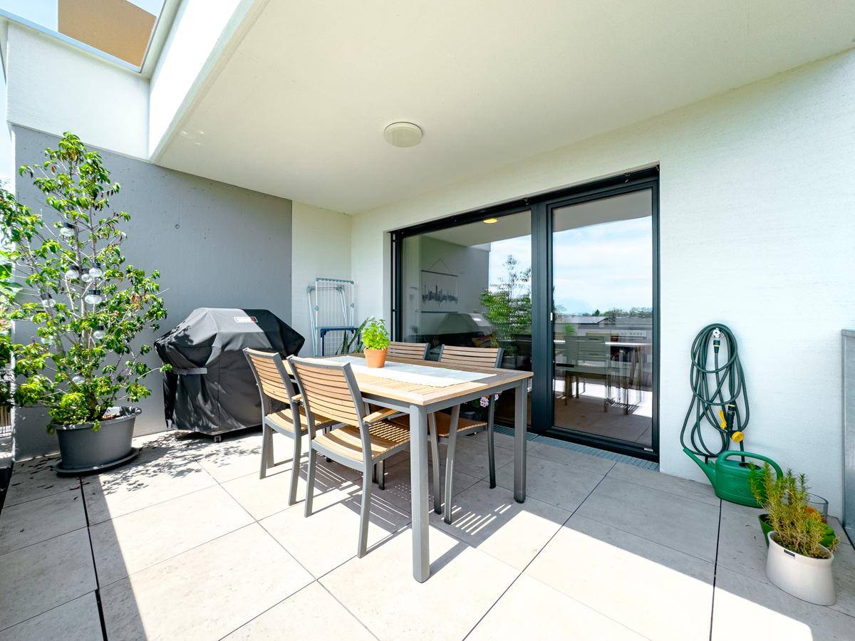 Geräumige Terrasse mit Esstisch, Grill und Pflanzen, ideal für Entspannung im Freien.
