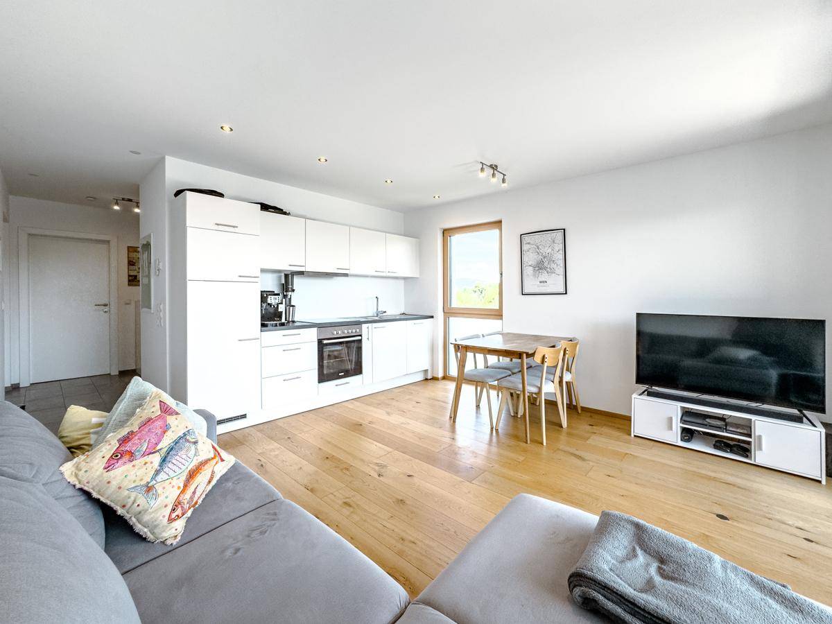 Geräumiger Wohn-Essbereich mit offener Küche, Sofa und Fernseher.