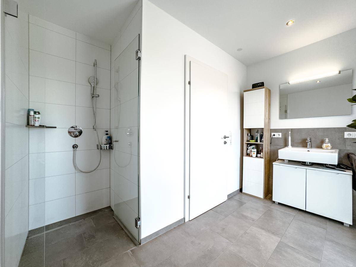 Modernes Badezimmer mit begehbarer Dusche, Waschtisch und Spiegelschrank.