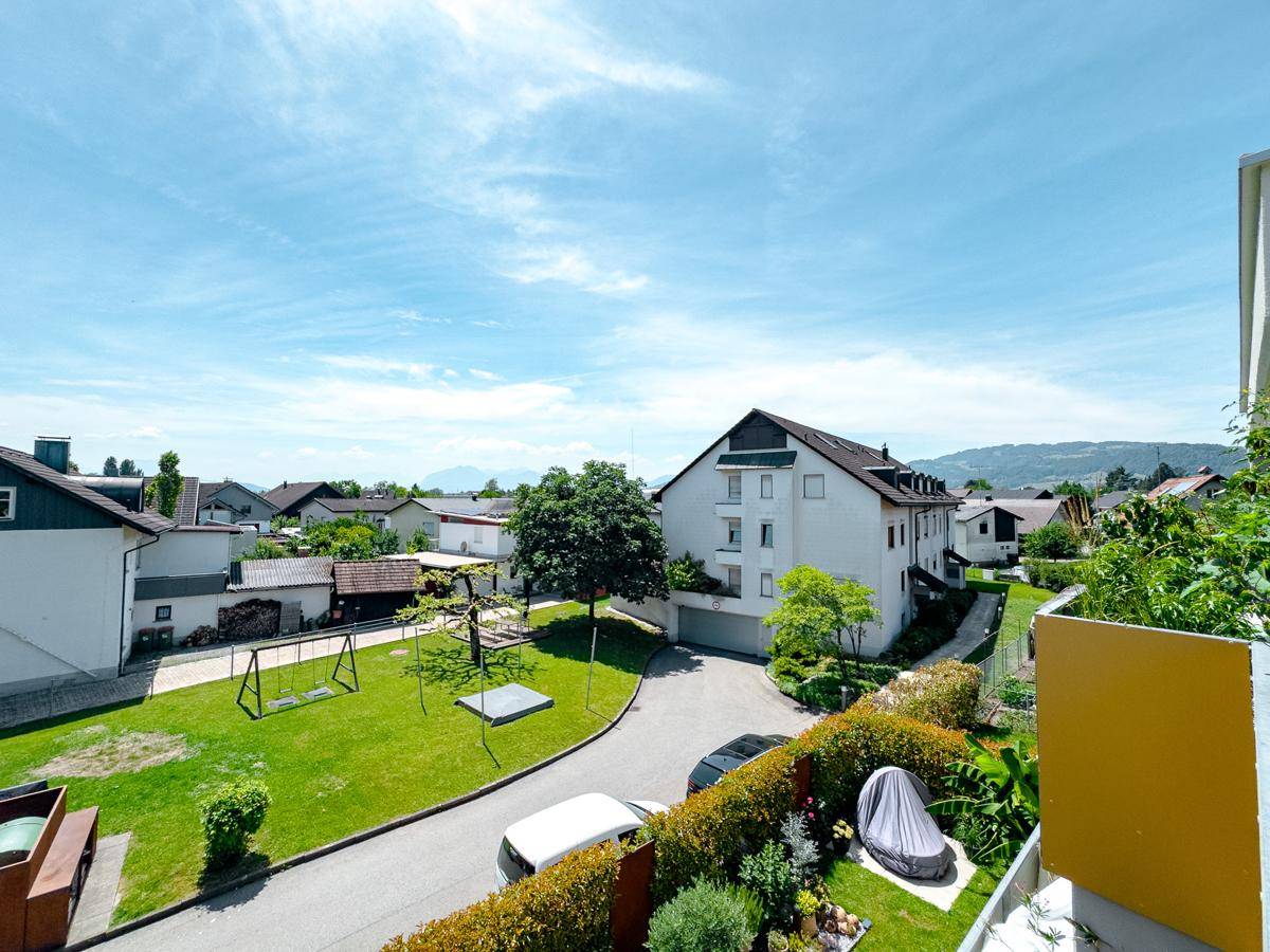 Blick auf die Nachbarschaft mit Wohnhäusern, Grünflächen und einem Spielplatz unter blauem Himmel.