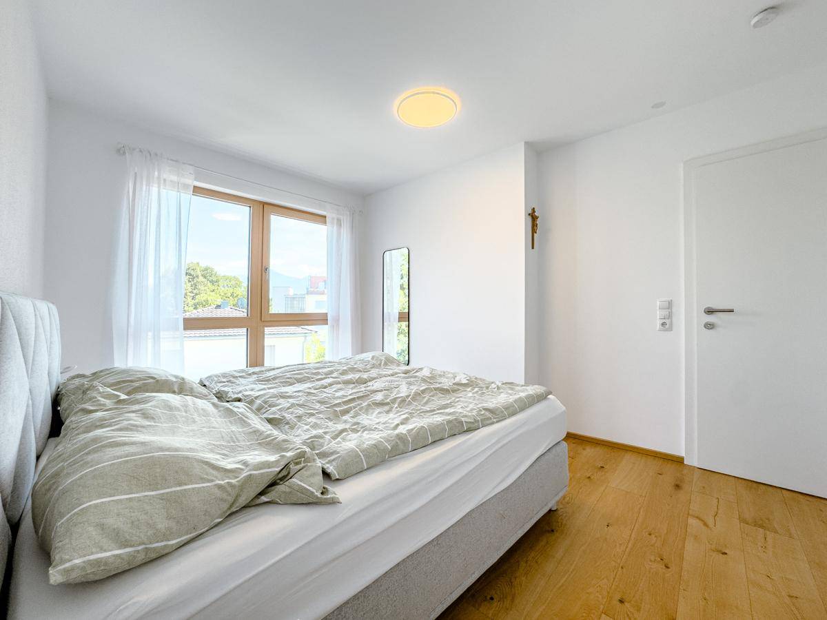 Gemütliches Schlafzimmer mit Holzboden, bequemen Bett und viel Tageslicht.