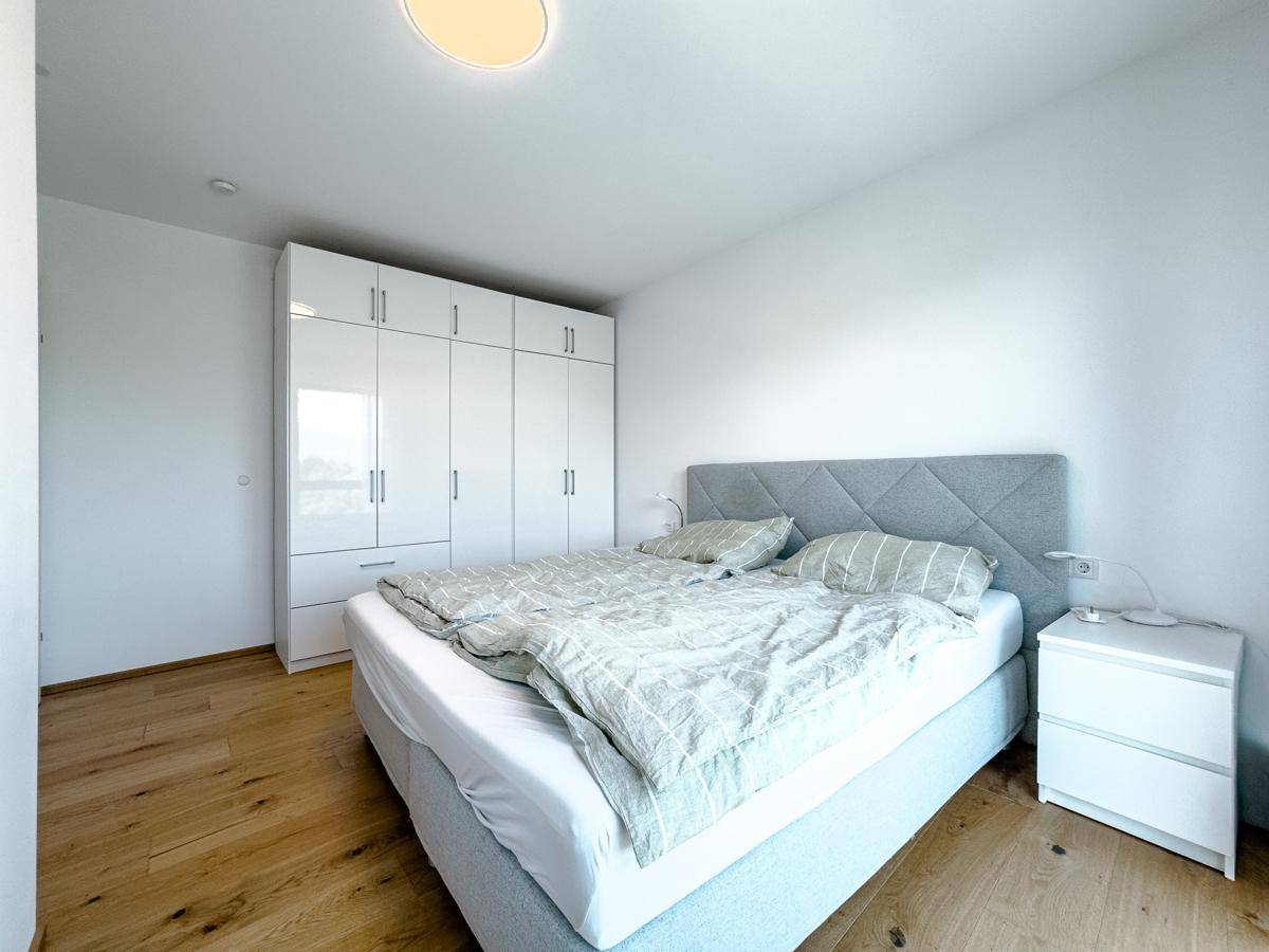 Schlafzimmer mit Holzboden, großem Kleiderschrank und modernem Doppelbett.