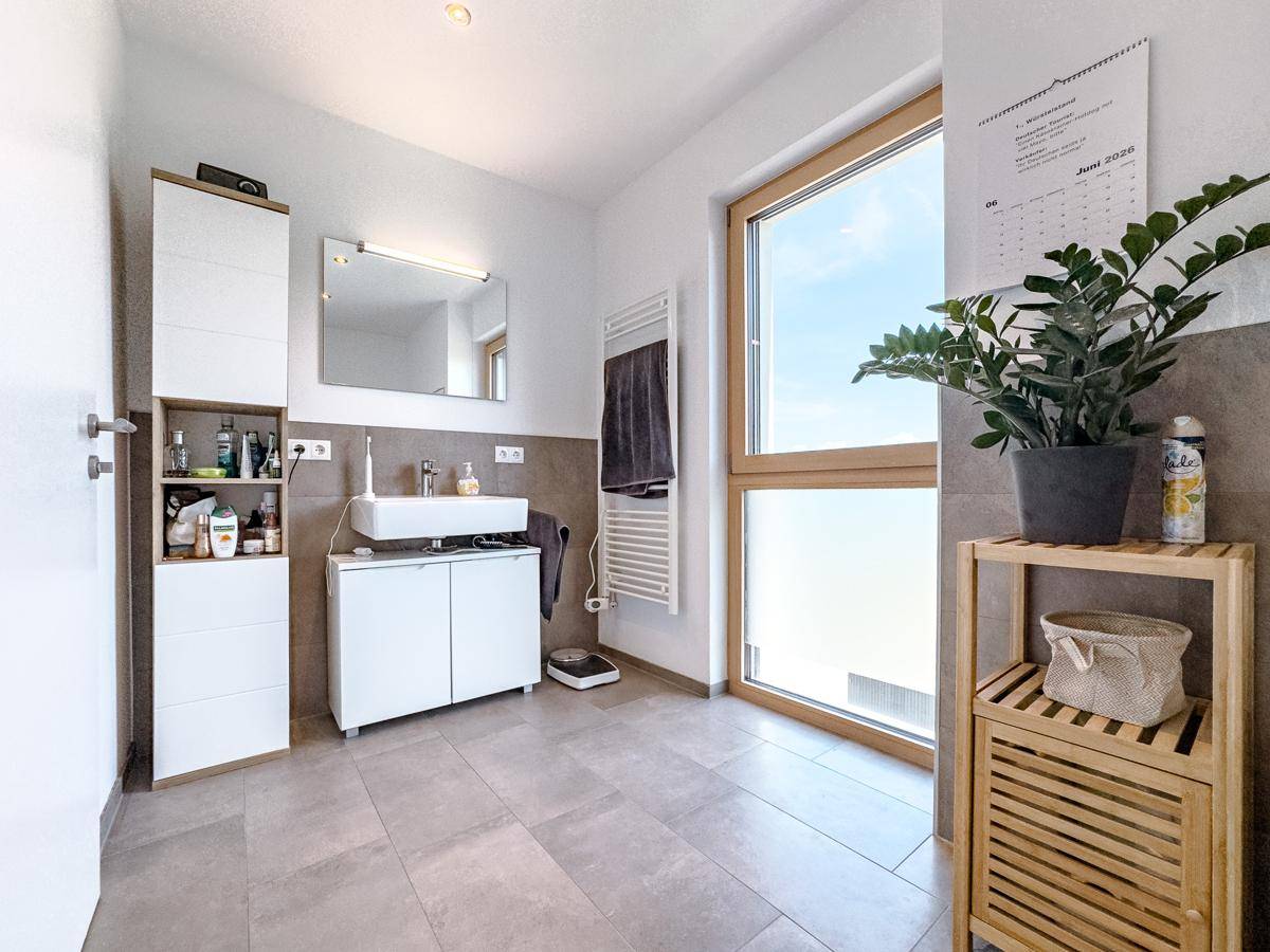 Modernes Badezimmer mit großem Fenster, Fliesenboden und weißem Waschtischunterschrank.
